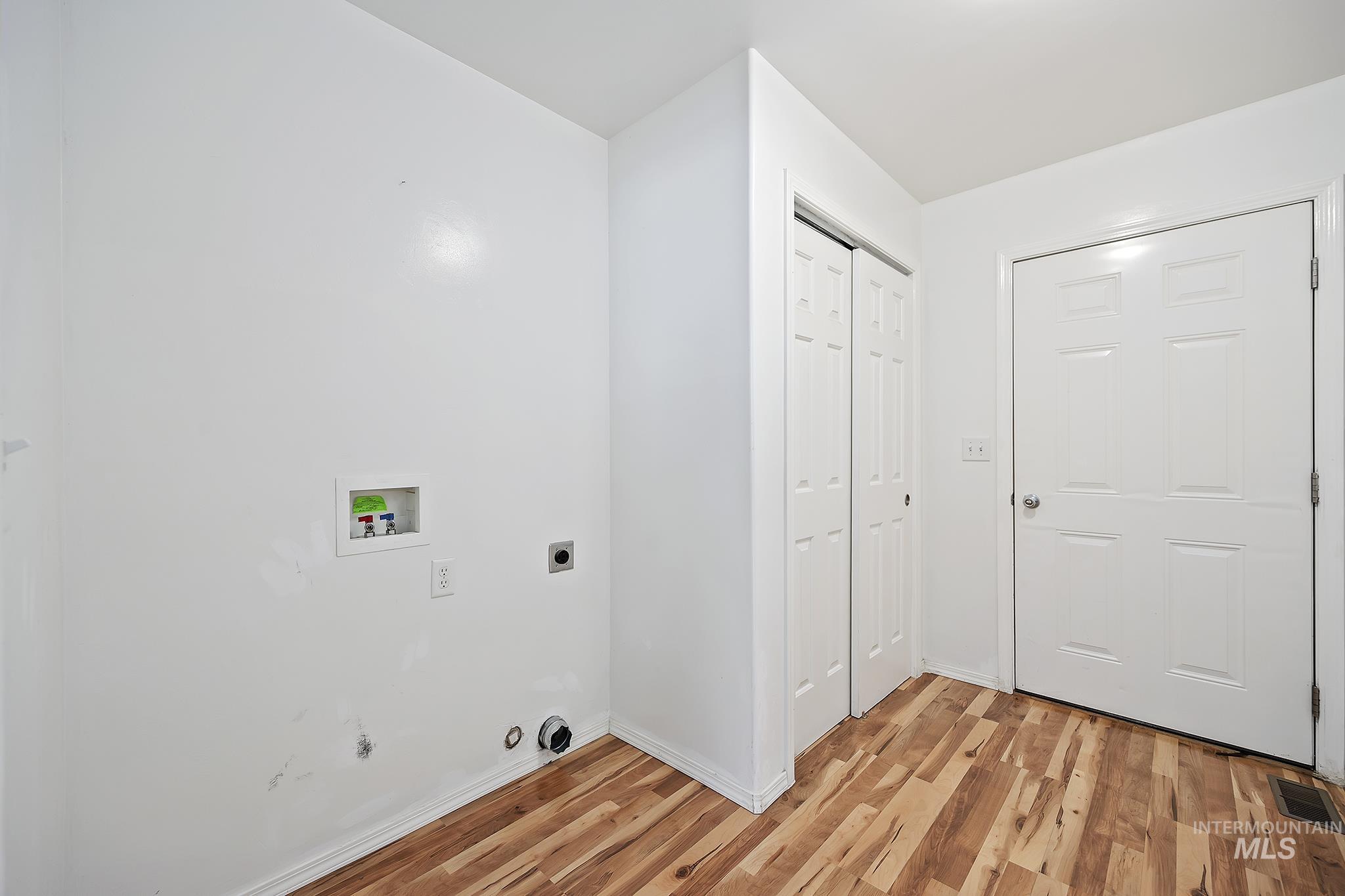 Washroom with hookup for a washing machine, light wood finished floors, hookup for an electric dryer, and hookup for a gas dryer