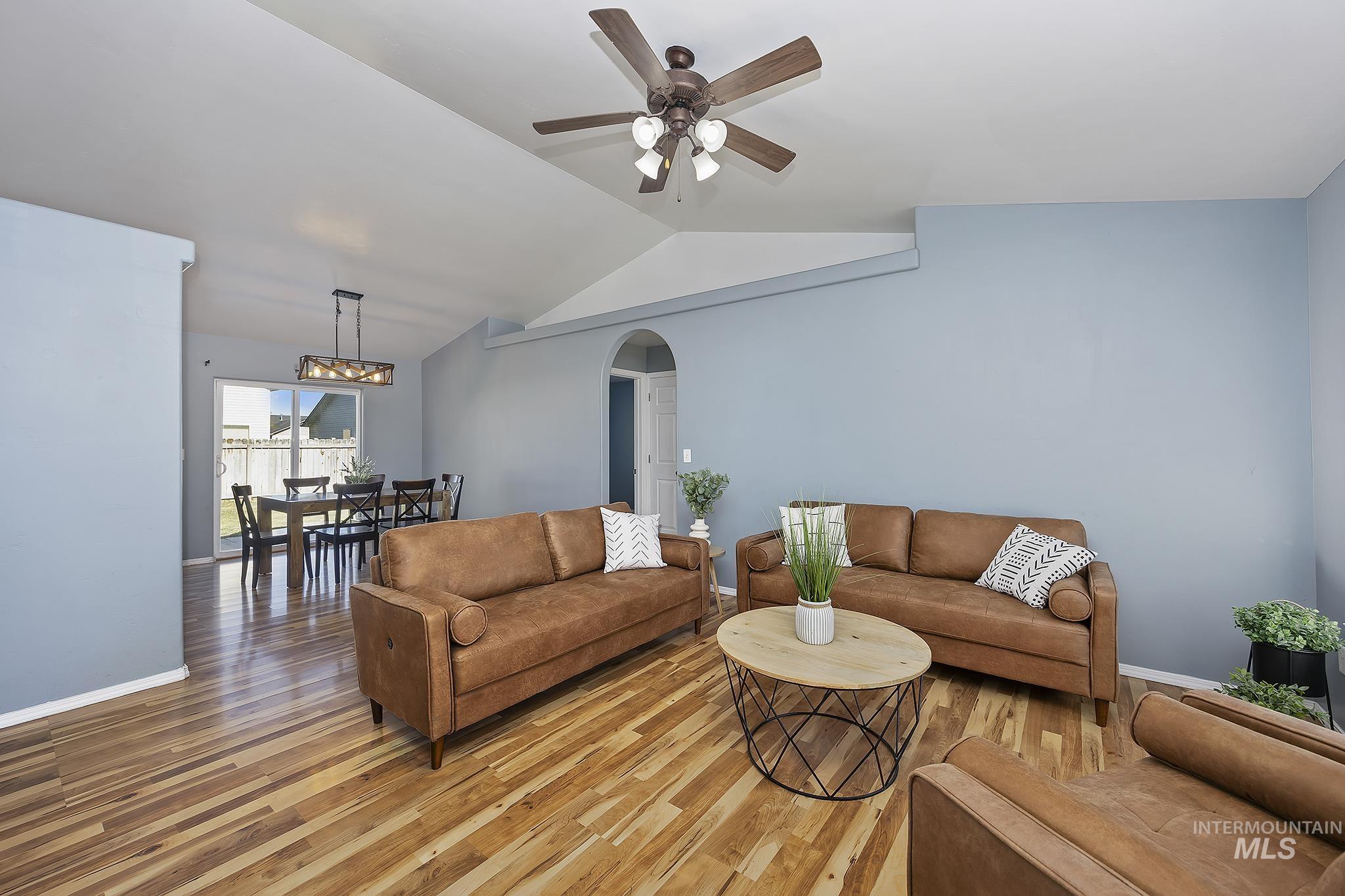 Living room with arched walkways, wood finished floors, lofted ceiling, and ceiling fan