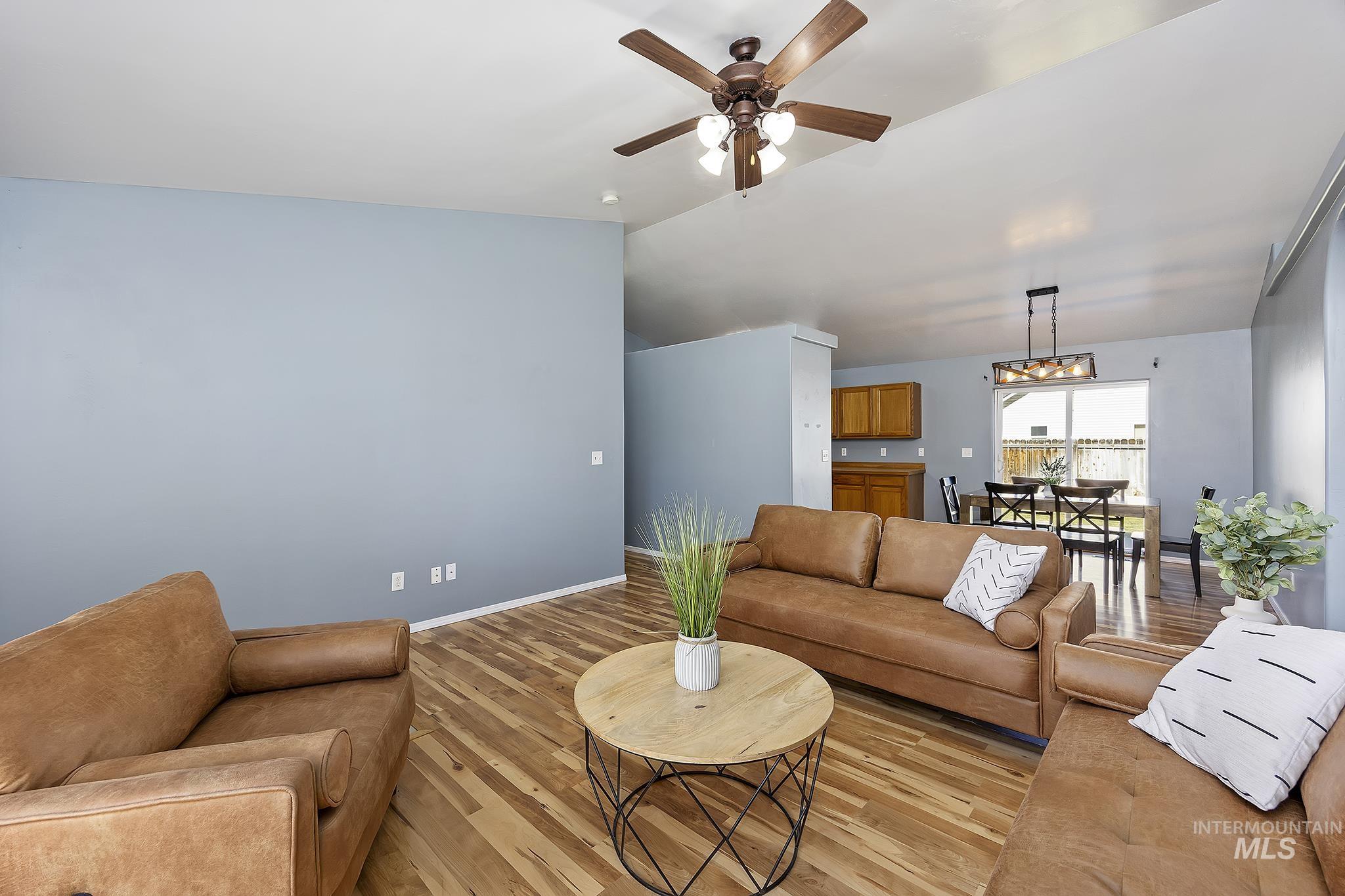 Living room featuring wood finished floors, vaulted ceiling, and a ceiling fan