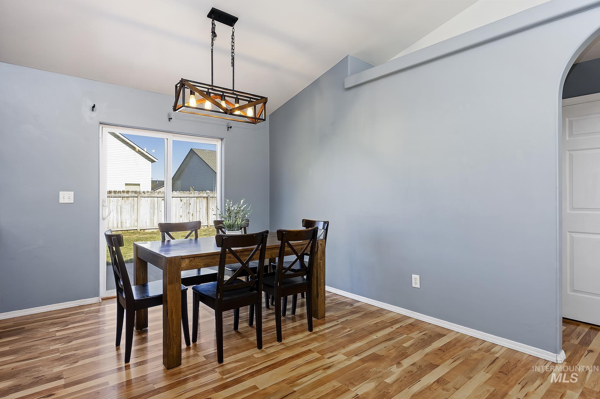 Dining area featuring vaulted ceiling, light wood-style floors, arched walkways, and a chandelier