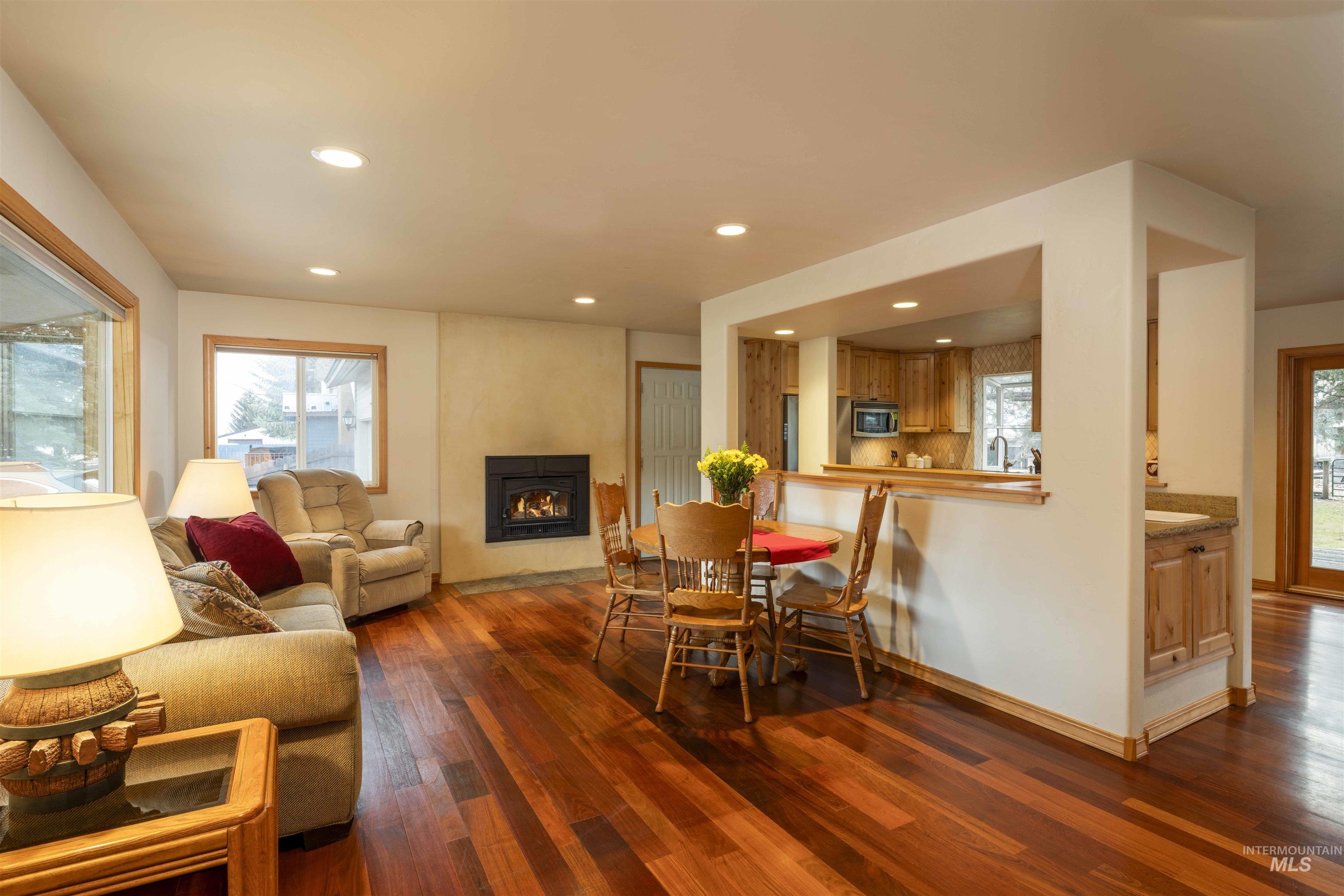 Dining space with dark wood finished floors, a glass covered fireplace, and recessed lighting