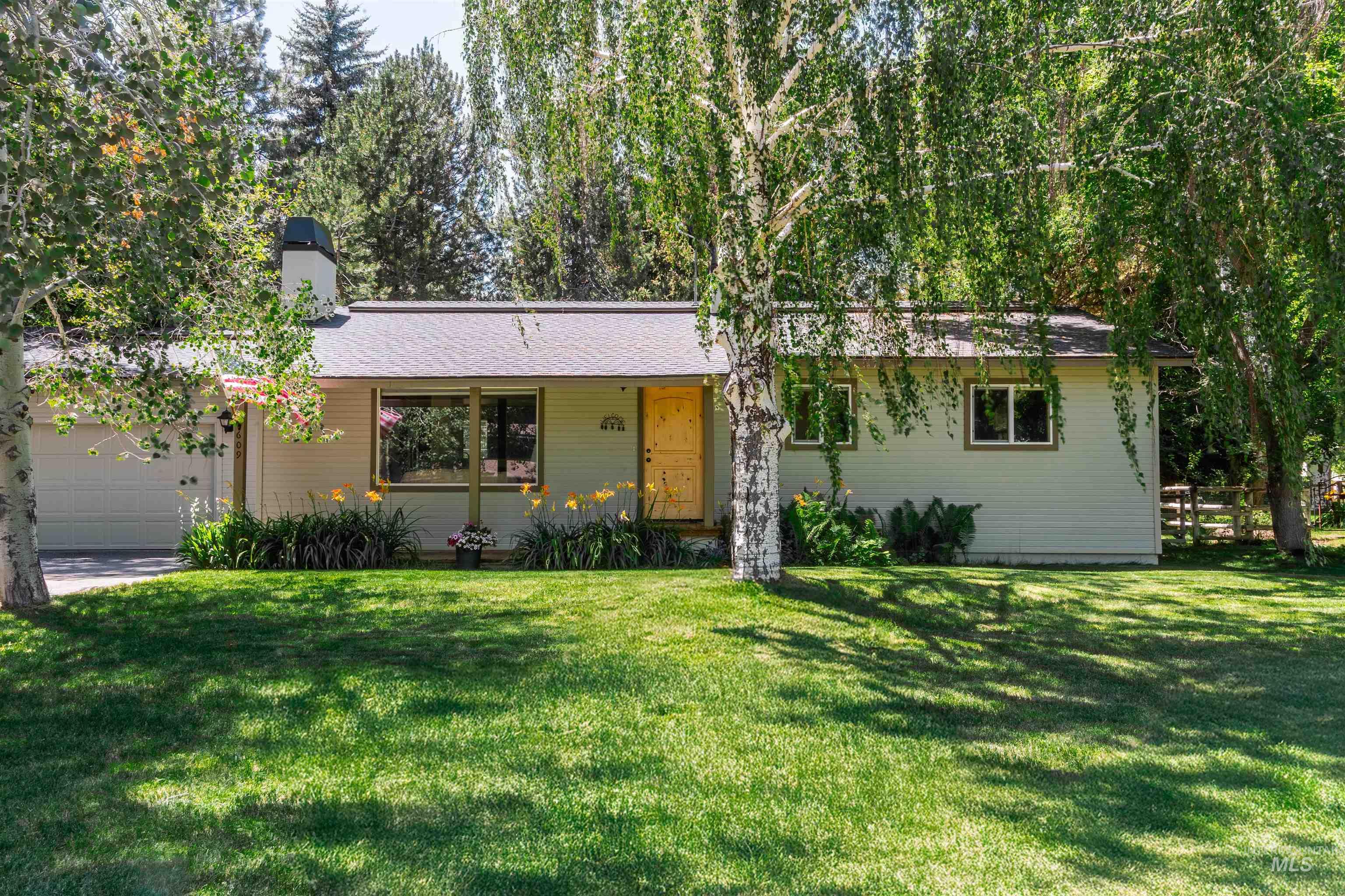 Ranch-style house with a chimney, a front yard, and an attached garage