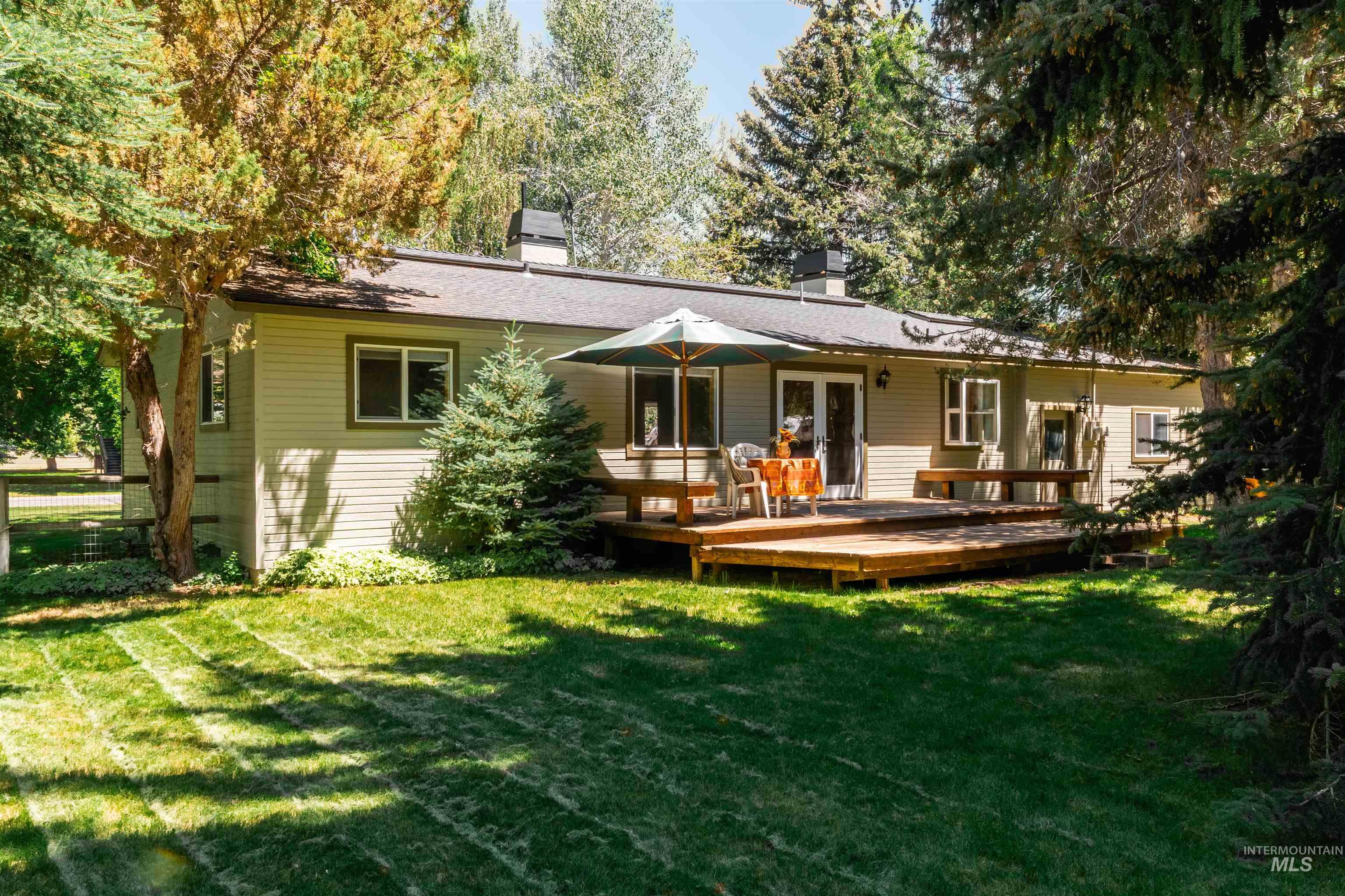 Rear view of property featuring a chimney, a lawn, and a deck
