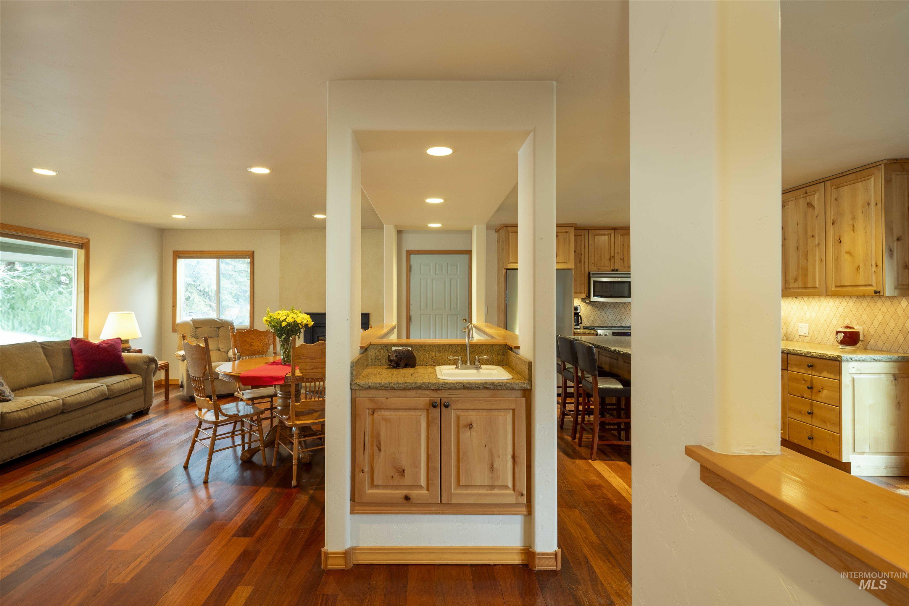 Kitchen with open floor plan, dark wood-style flooring, tasteful backsplash, and recessed lighting