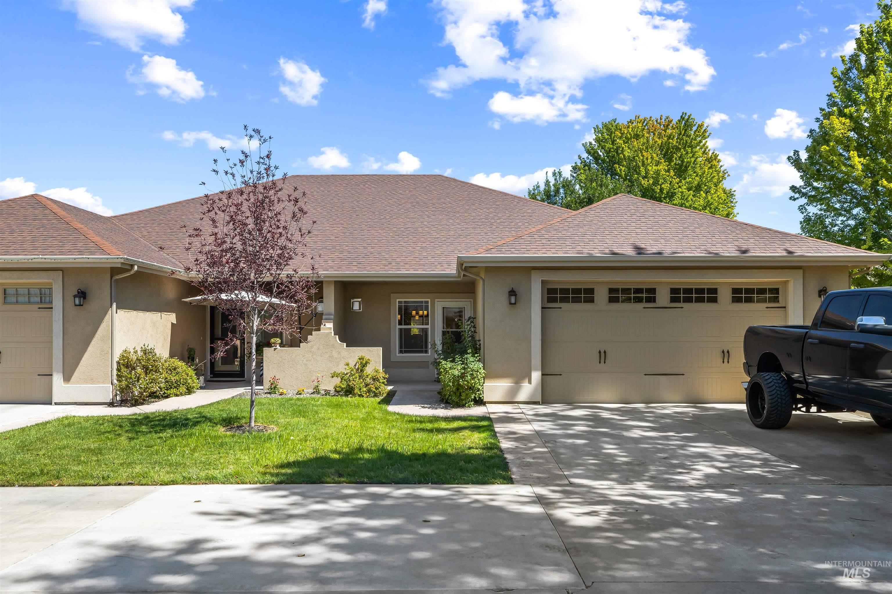 Ranch-style house with a garage, stucco siding, concrete driveway, roof with shingles, and a front yard