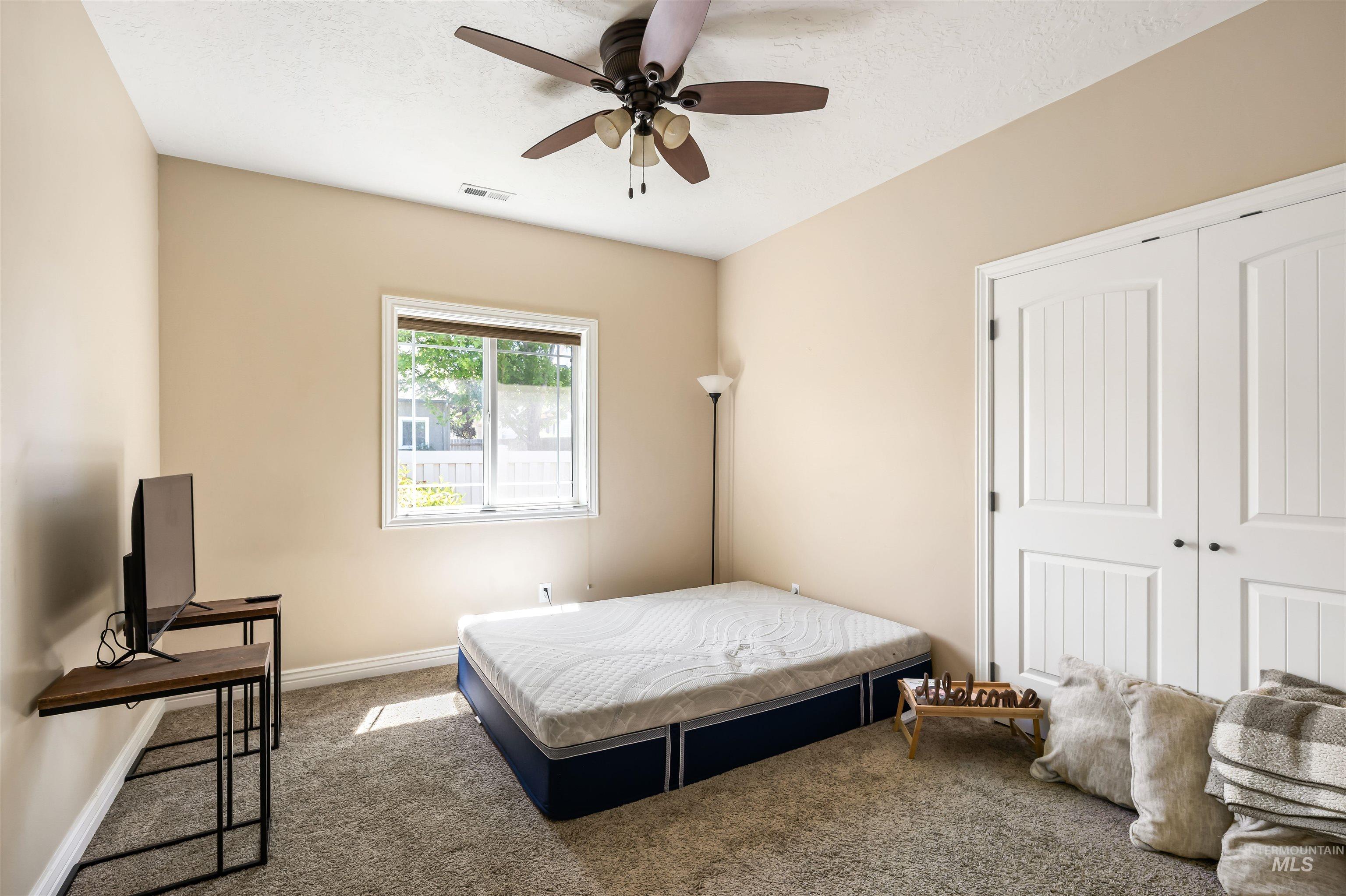 Bedroom featuring carpet floors, a ceiling fan, a closet, and a textured ceiling