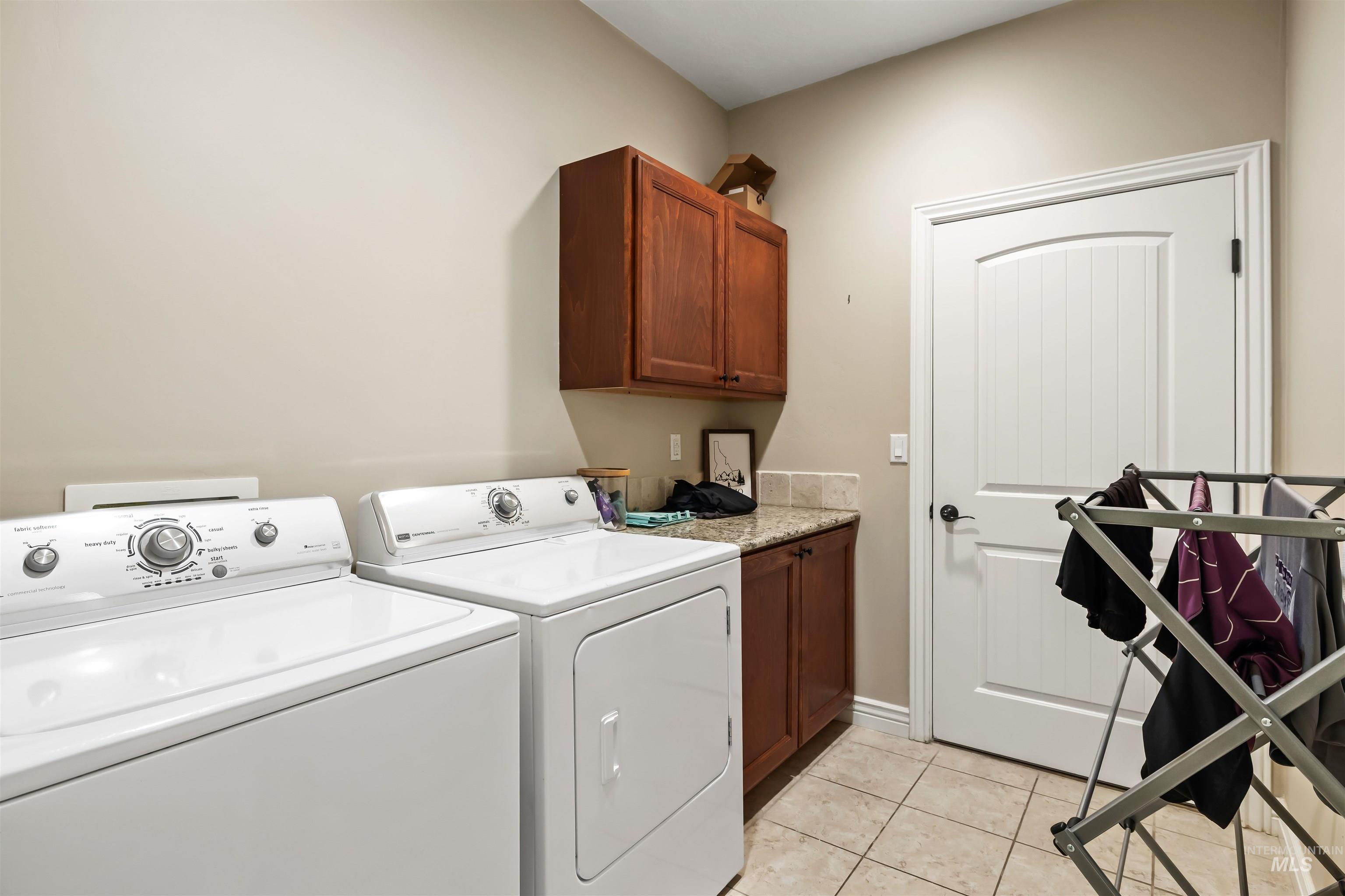 Laundry area with light tile patterned floors, cabinet space, and washing machine and dryer
