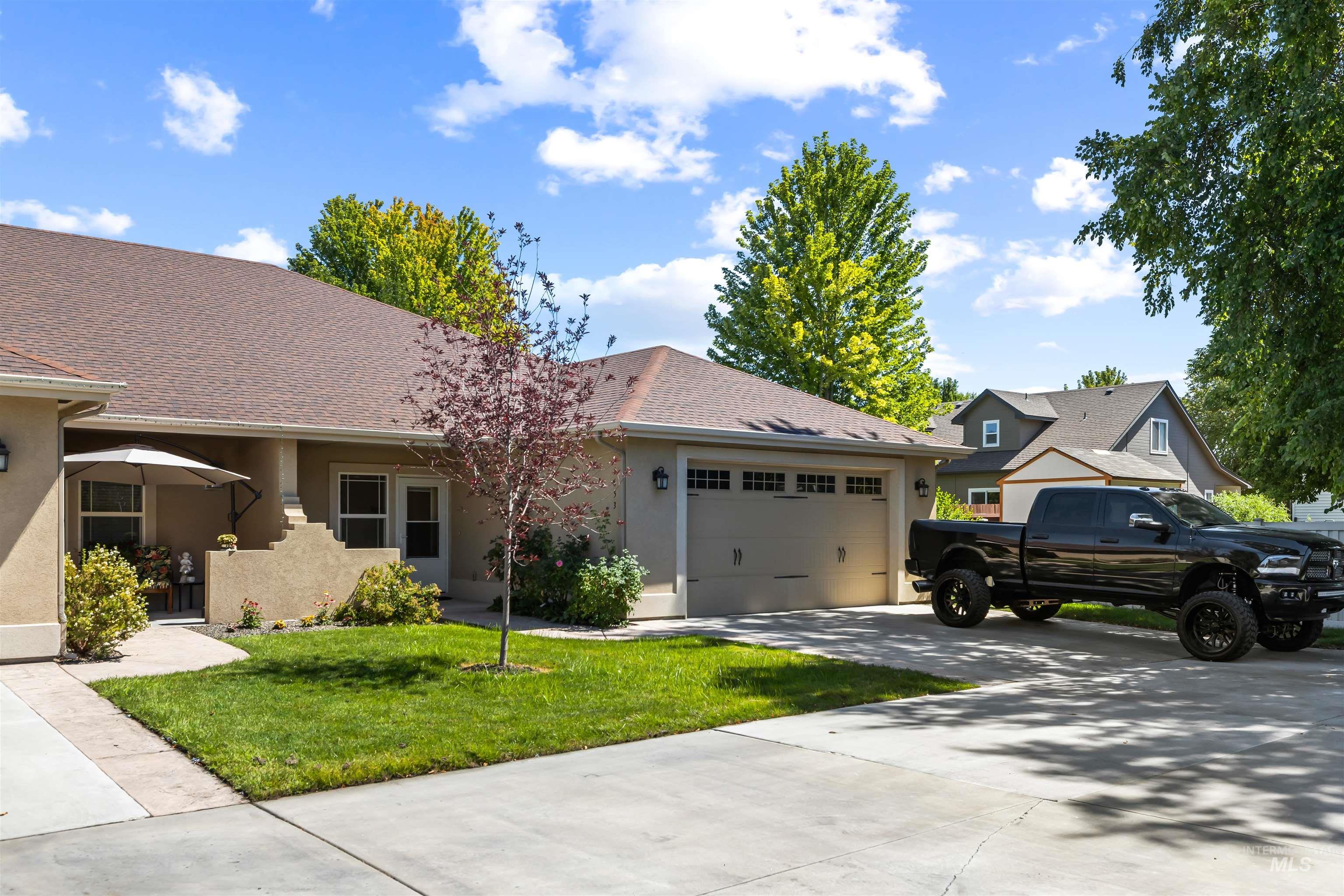 Ranch-style house featuring stucco siding, concrete driveway, a garage, a front lawn, and roof with shingles