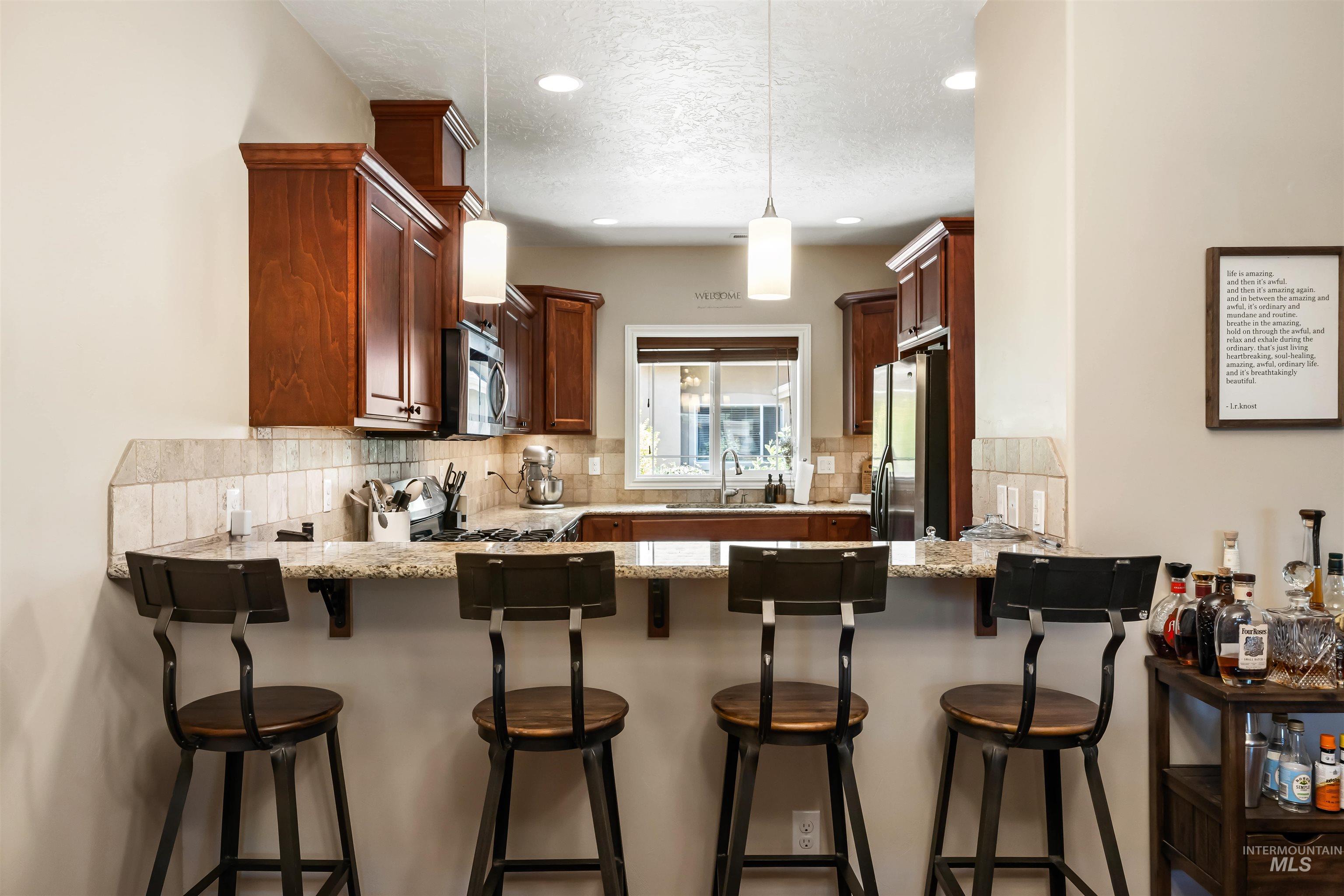 Kitchen with decorative backsplash, light stone counters, pendant lighting, appliances with stainless steel finishes, and recessed lighting