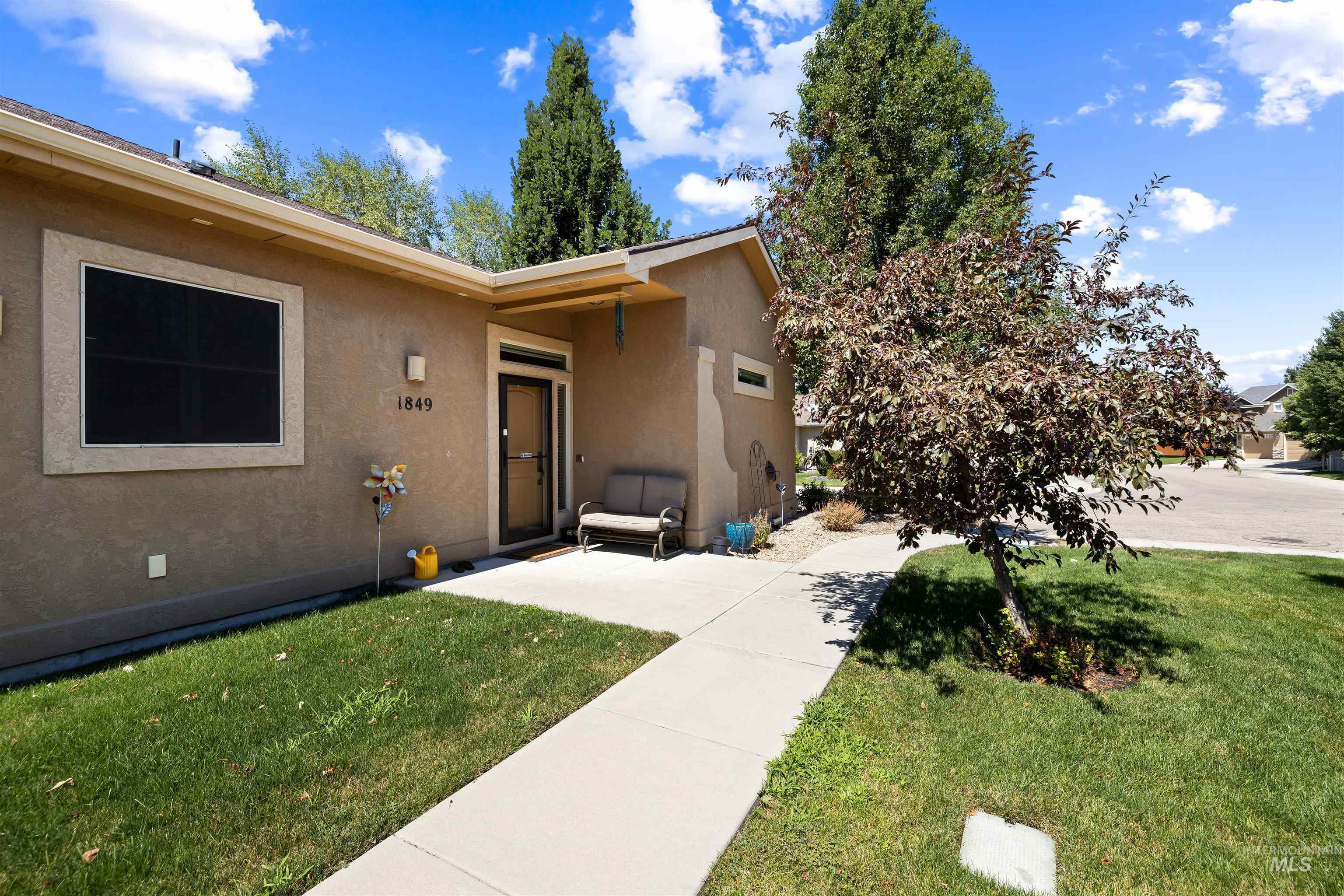 View of exterior entry with stucco siding and a lawn
