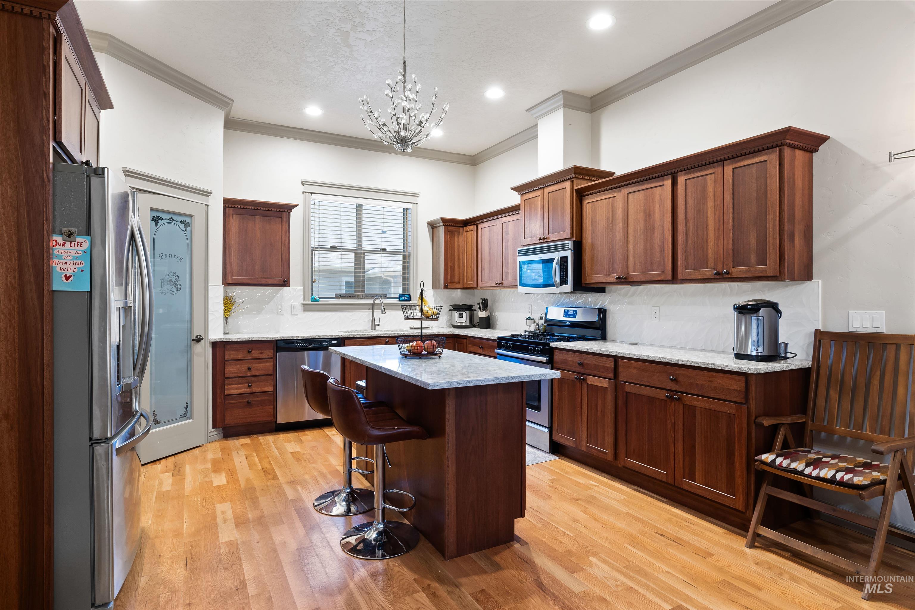 Kitchen featuring stainless steel appliances, a breakfast bar, tasteful backsplash, light wood finished floors, and a center island