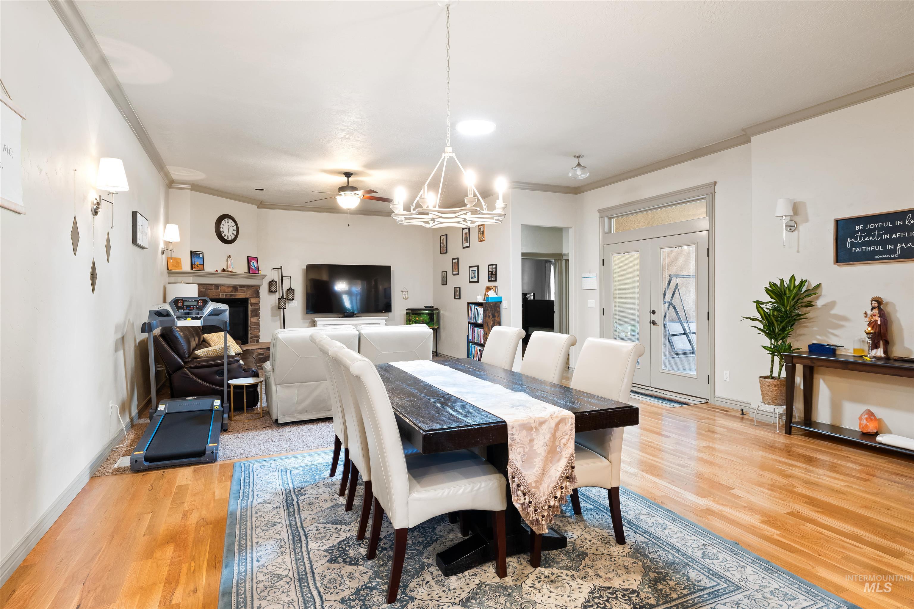 Dining space featuring ornamental molding, light wood-type flooring, a stone fireplace, and a ceiling fan
