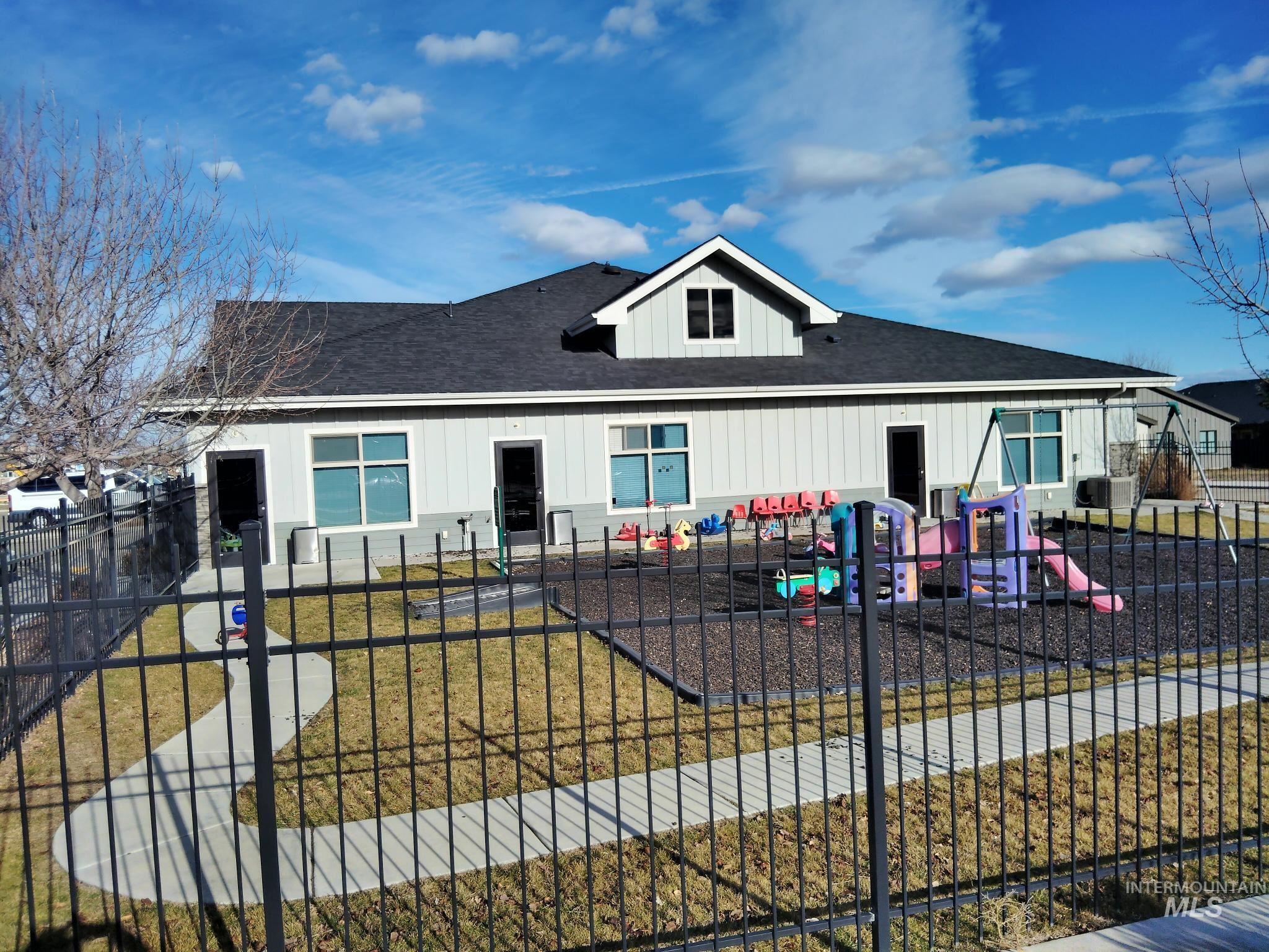 View of front of house featuring board and batten siding, roof with shingles, and a playground
