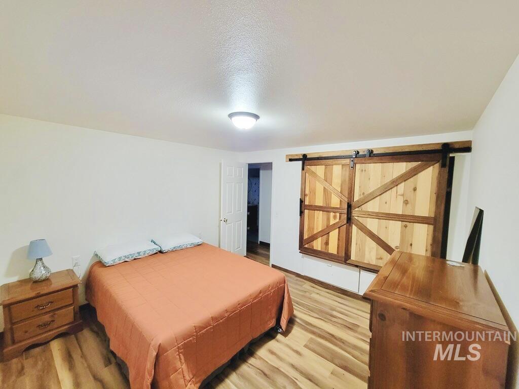 Bedroom with a barn door, wood finished floors, and a textured ceiling