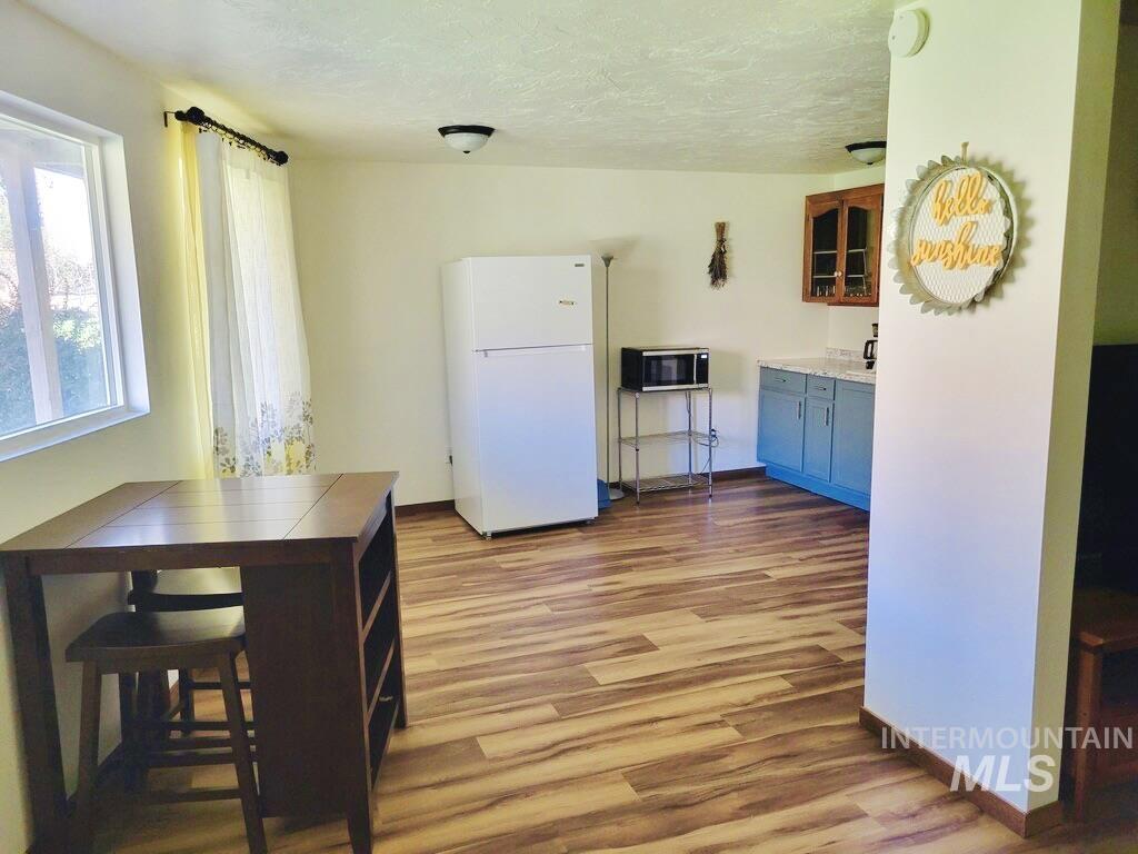 Kitchen featuring freestanding refrigerator, light countertops, glass insert cabinets, dark wood-style floors, and a textured ceiling