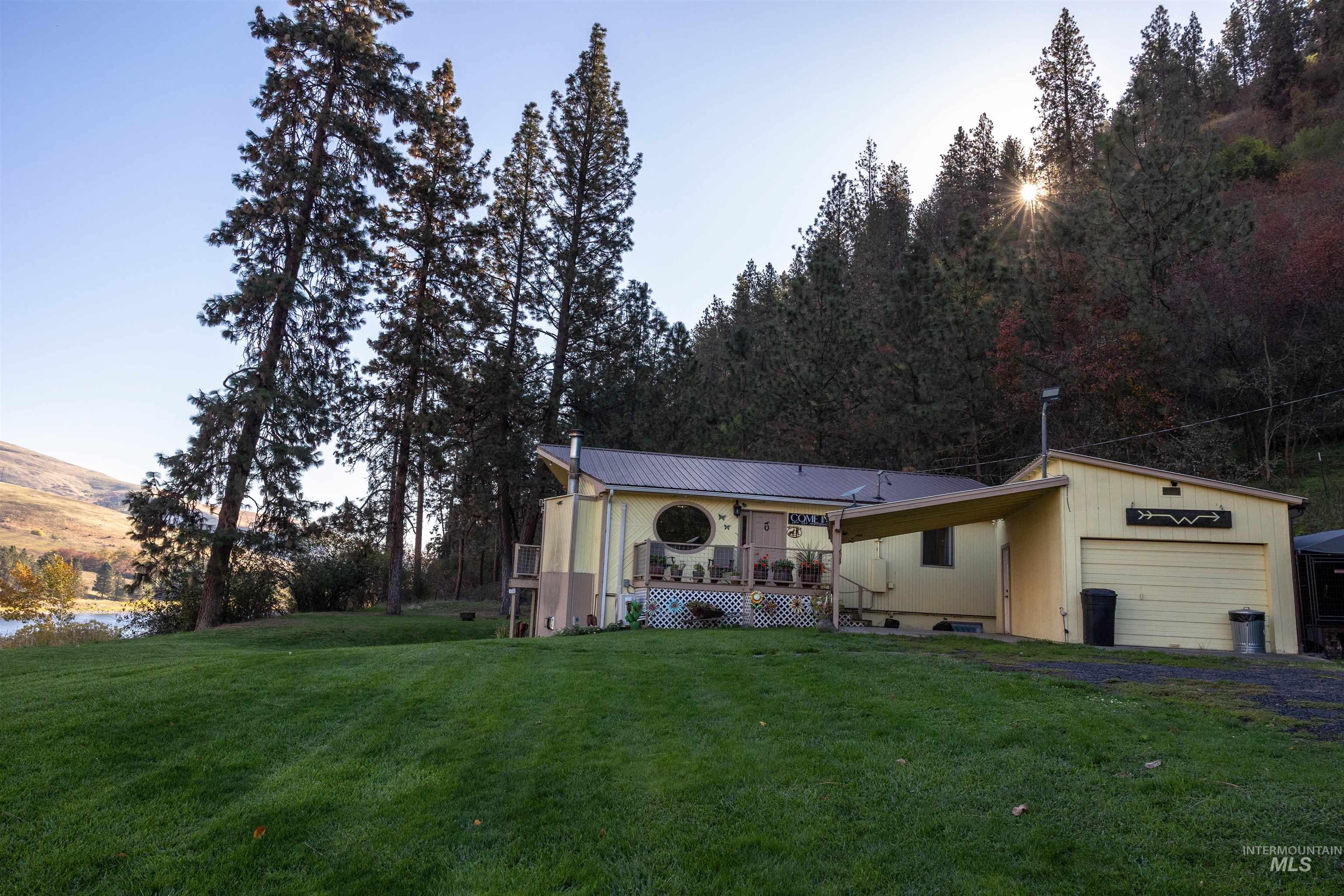 View of front of home with a wooden deck, a front yard, a metal roof, and a garage