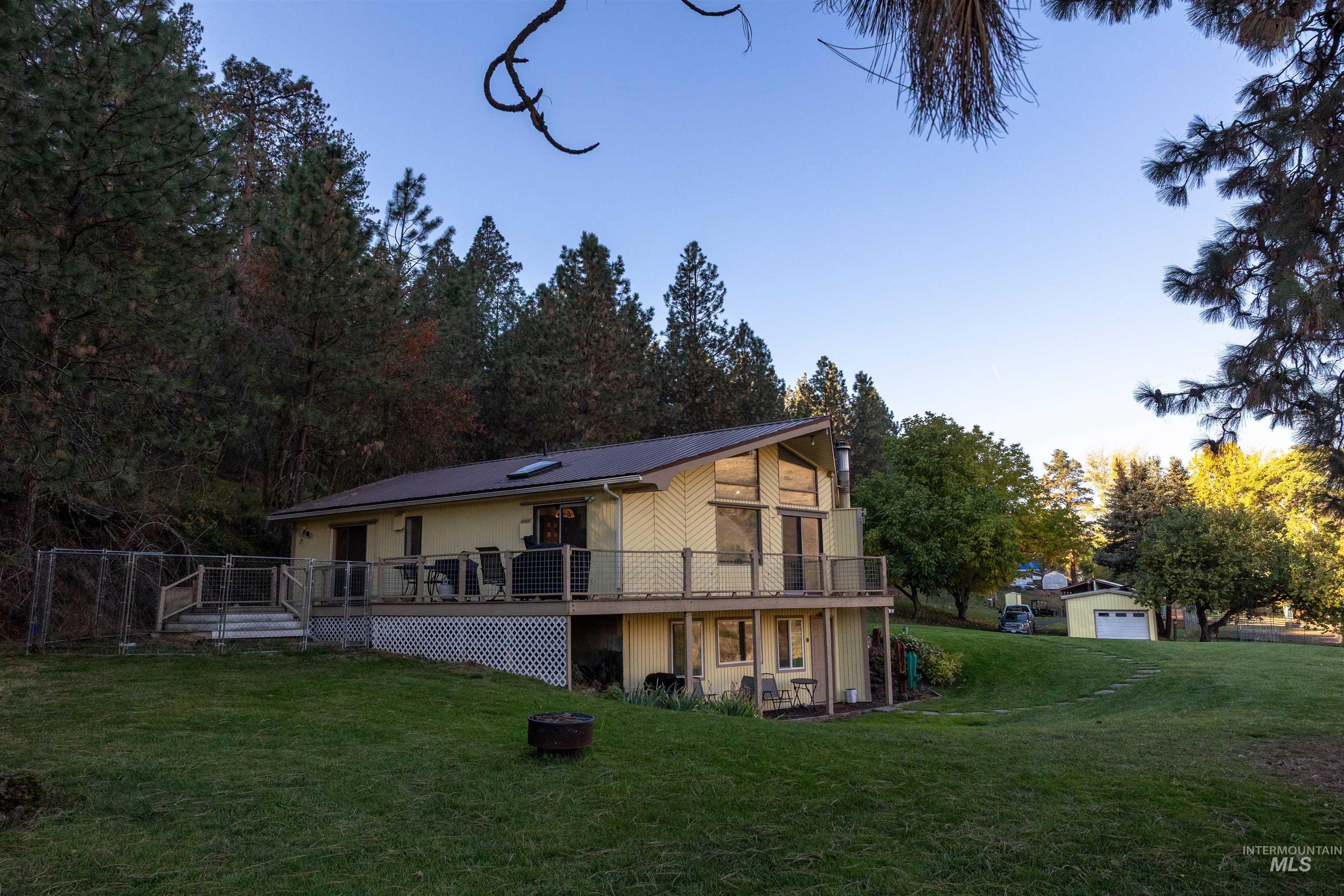 Back of house featuring a yard, a deck, and a fire pit