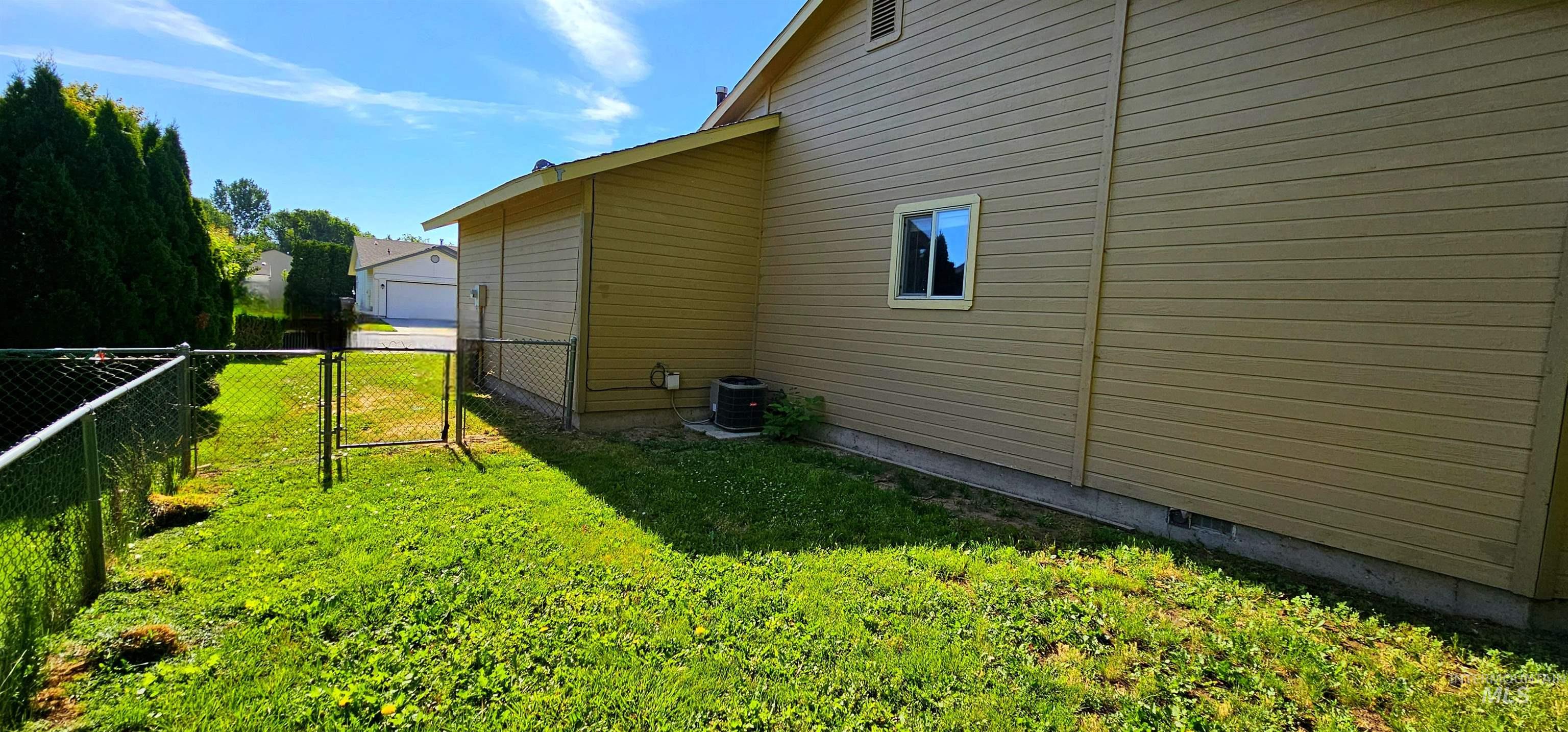 View of side of property with a gate and a cooling unit