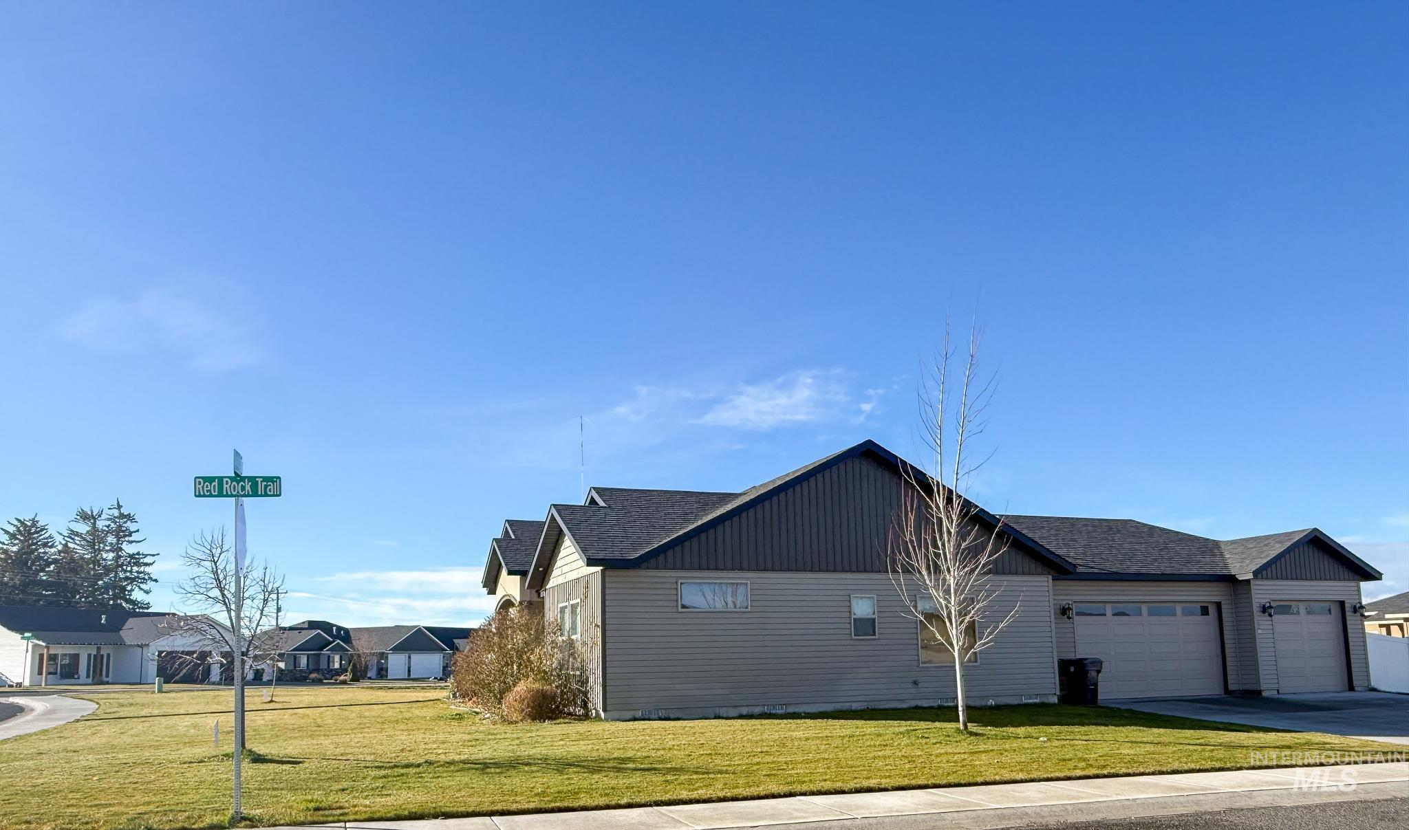 View of property exterior featuring a yard, a garage, and concrete driveway