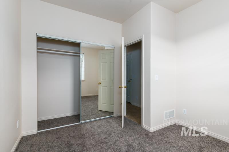 Unfurnished bedroom featuring dark colored carpet and a closet