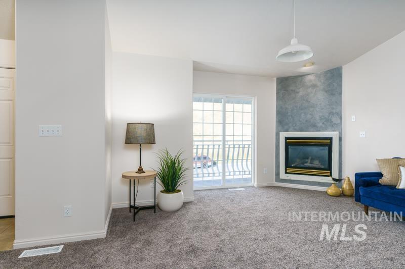 Living area with light colored carpet and a large fireplace