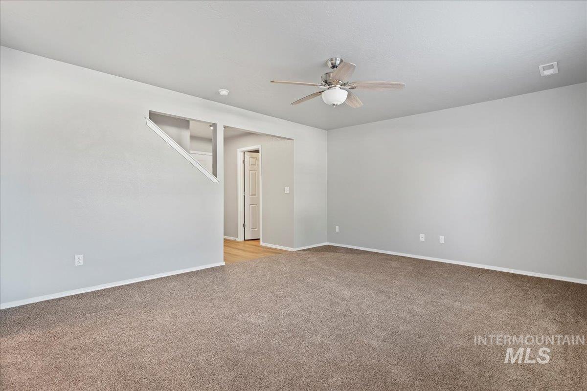 Empty room with light colored carpet and ceiling fan