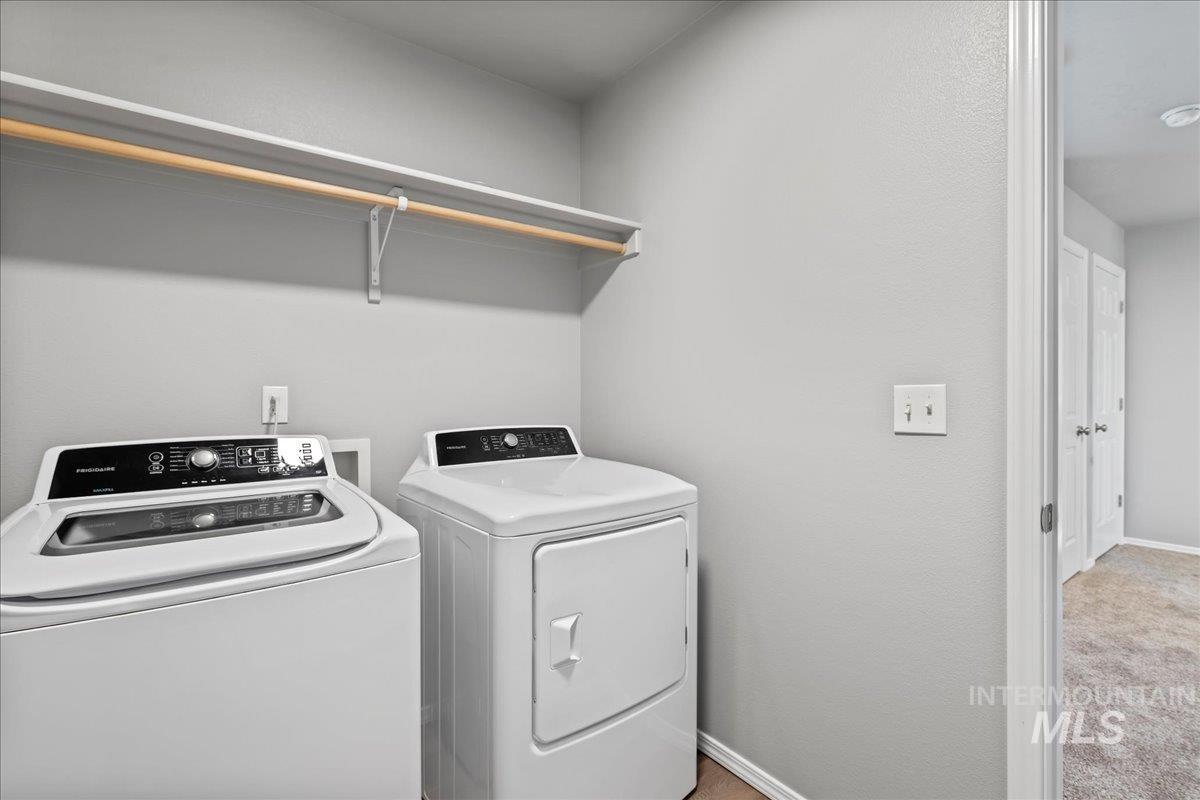 Laundry room with light colored carpet and washing machine and dryer