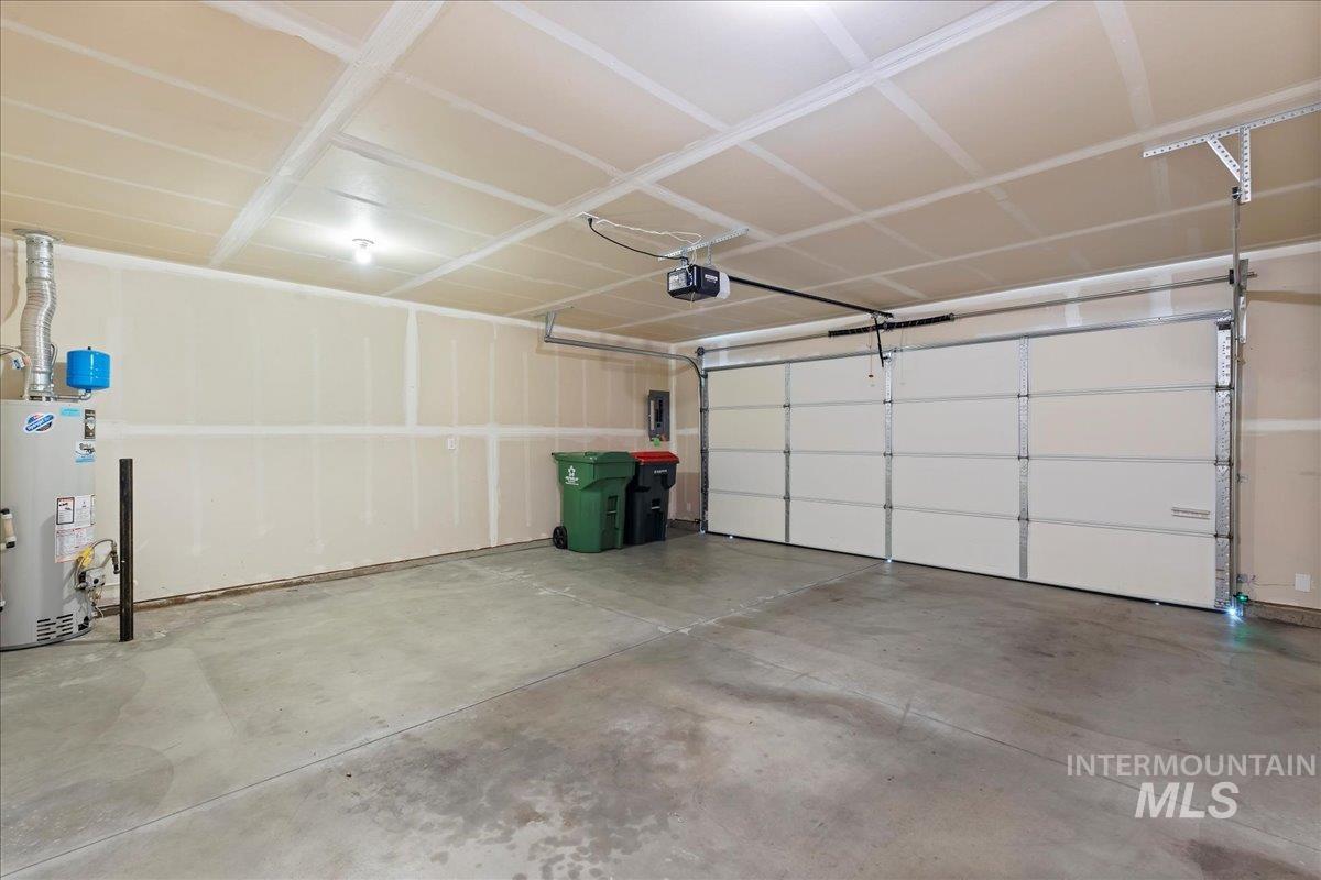 Garage with water heater, electric panel, and a garage door opener