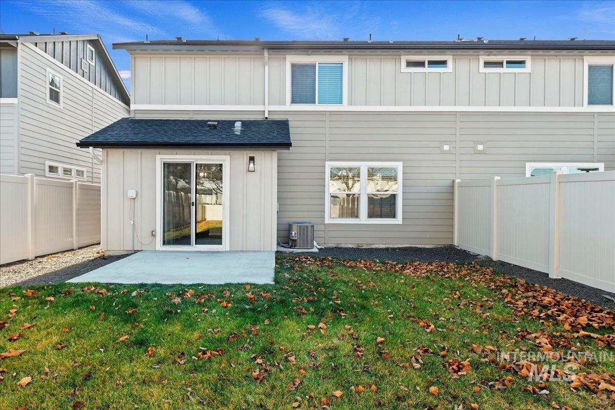 Back of house with board and batten siding, a patio, and a fenced backyard