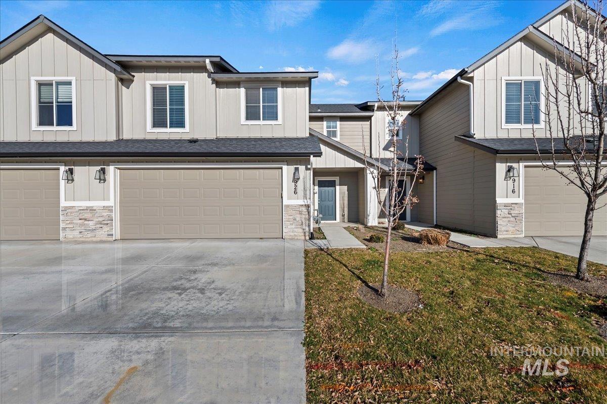 View of front facade featuring an attached garage, stone siding, concrete driveway, and board and batten siding