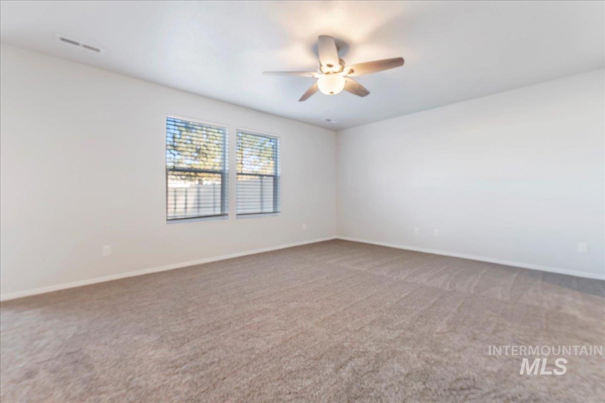 Spare room featuring light colored carpet and a ceiling fan