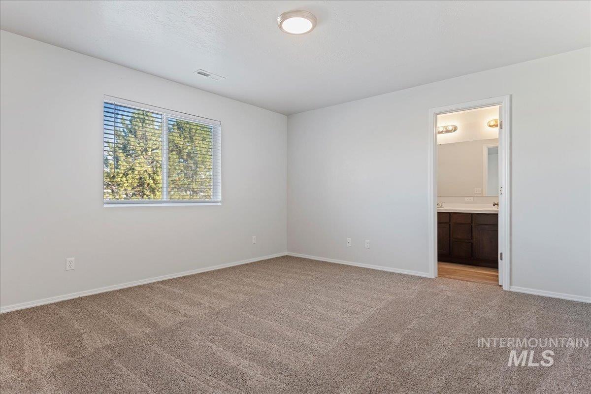 Unfurnished bedroom featuring light colored carpet and ensuite bath