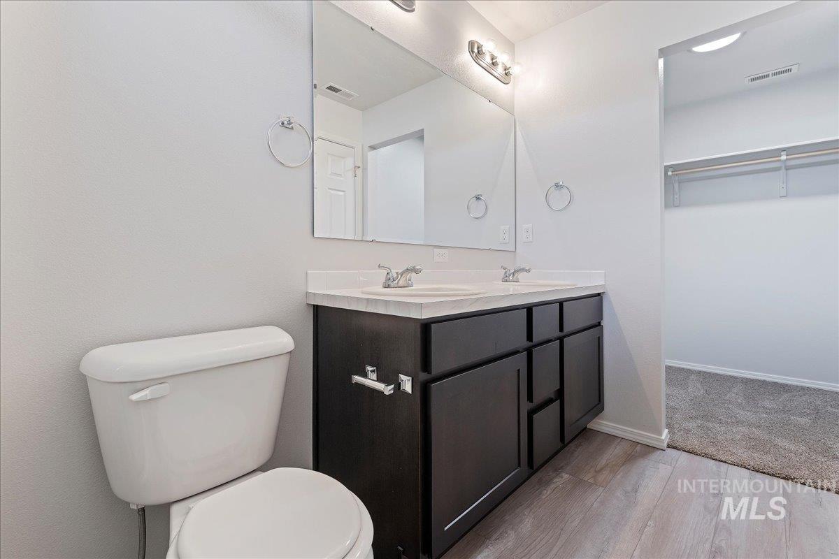 Bathroom featuring double vanity, light wood finished floors, and a walk in closet