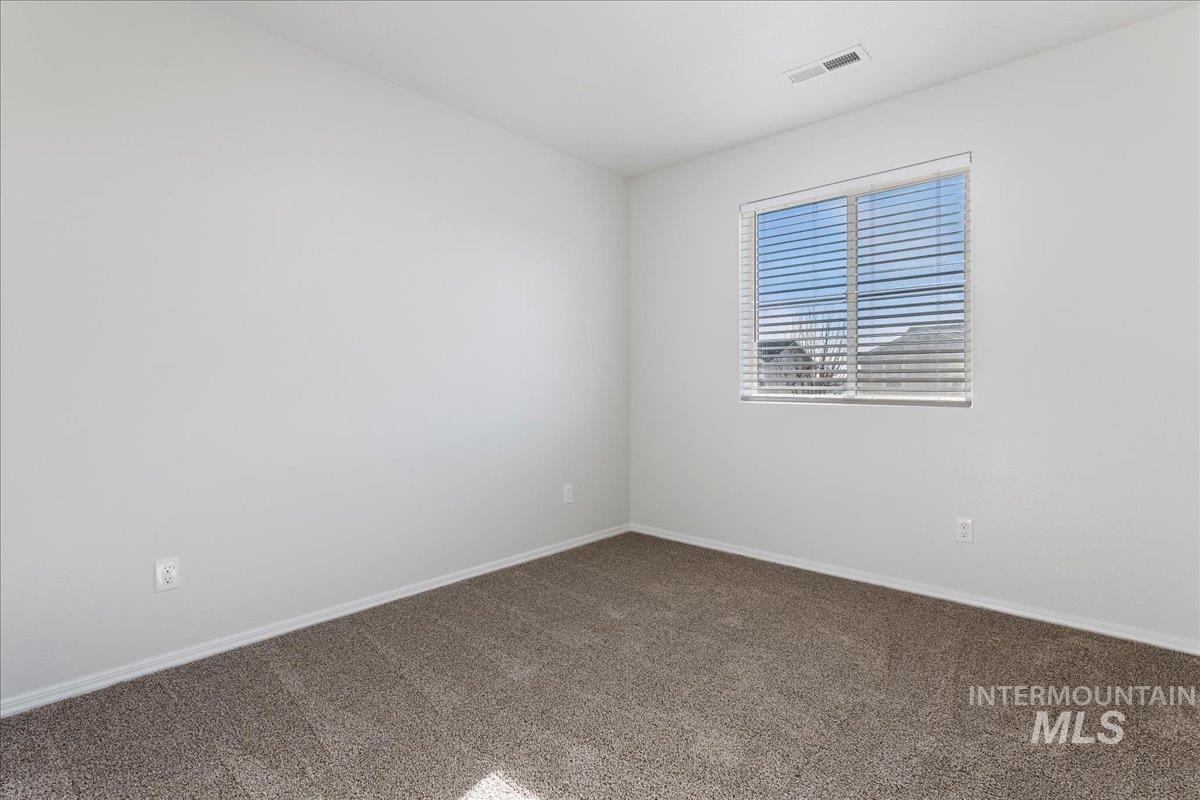 Carpeted spare room featuring baseboards