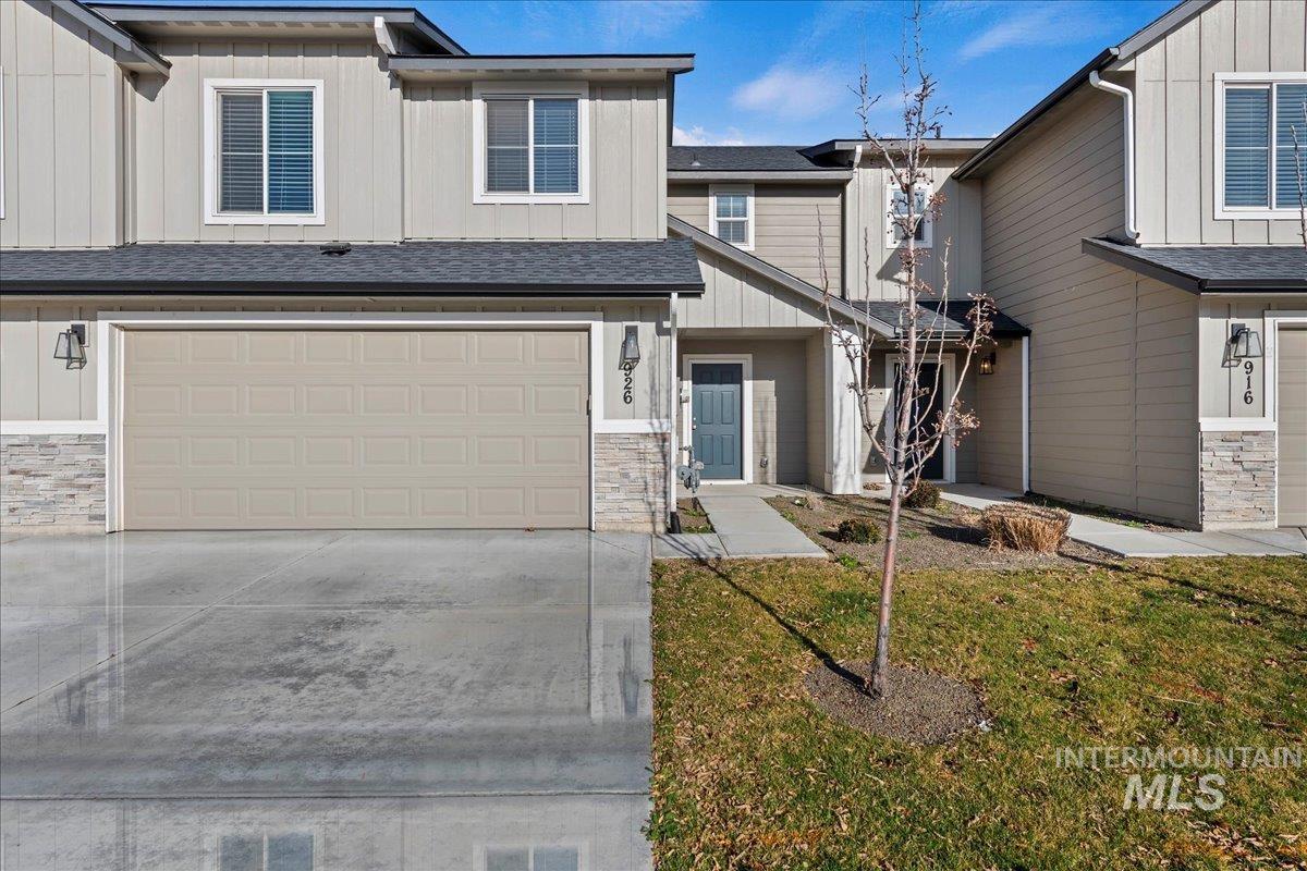 Craftsman-style home featuring stone siding, board and batten siding, a front lawn, driveway, and a garage