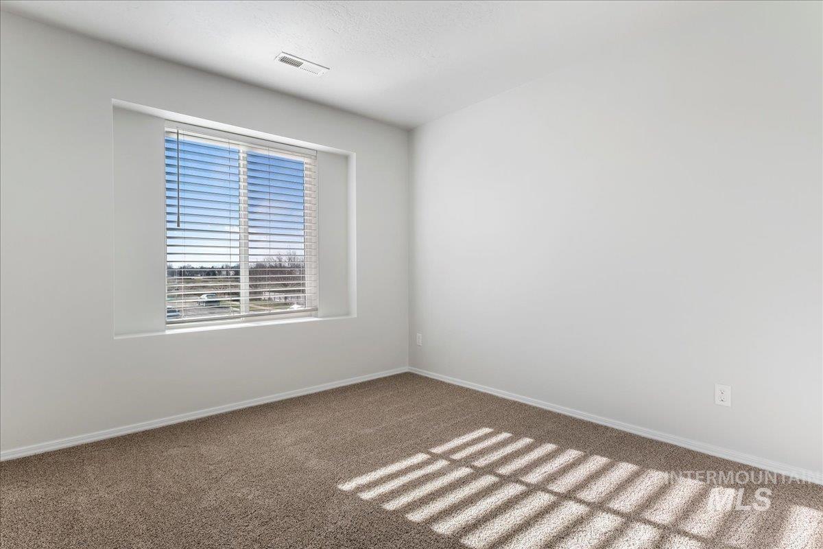 Carpeted spare room featuring baseboards