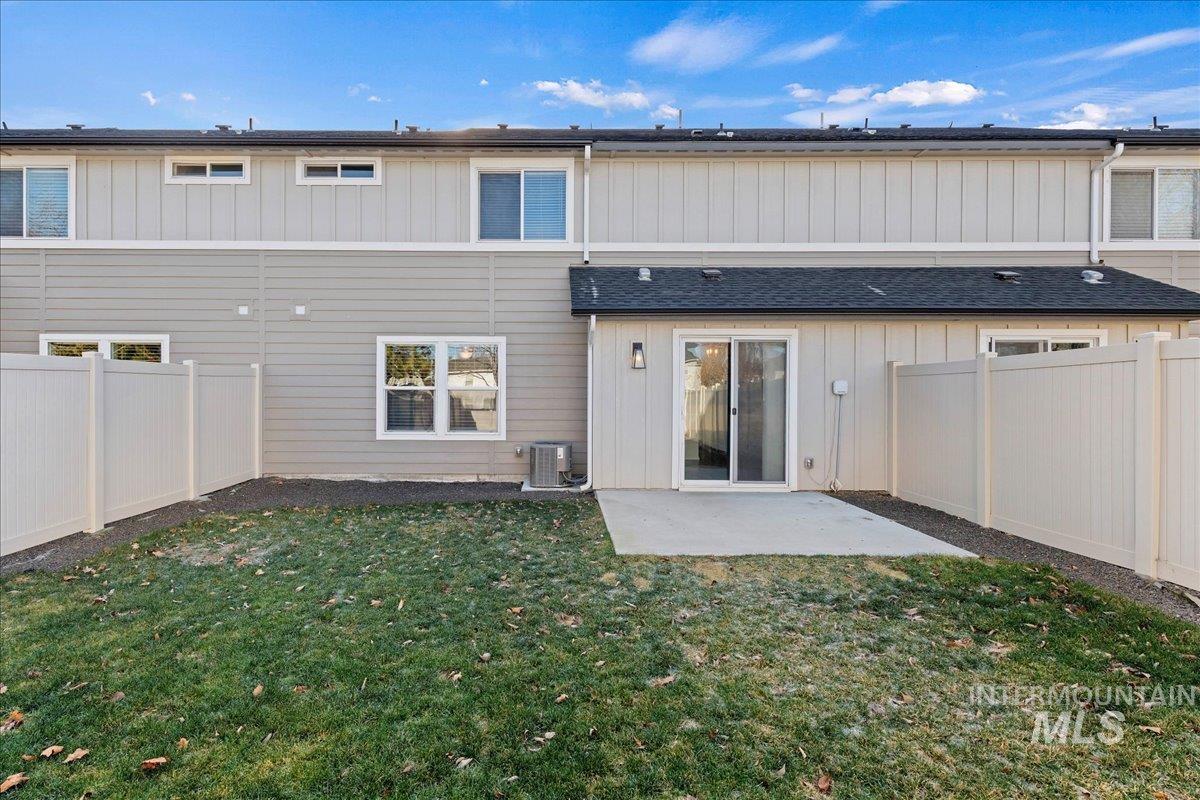 Rear view of property with a fenced backyard, a patio, board and batten siding, and roof with shingles