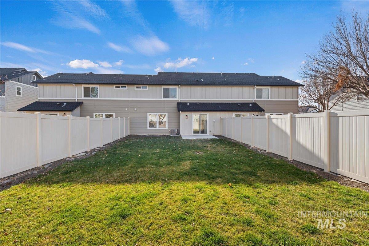 Back of property featuring a fenced backyard, a patio, and board and batten siding