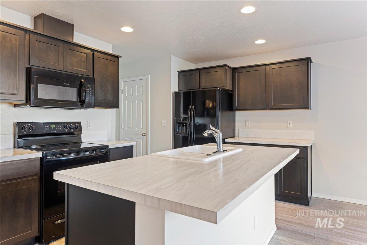 Kitchen with black appliances, light countertops, and recessed lighting