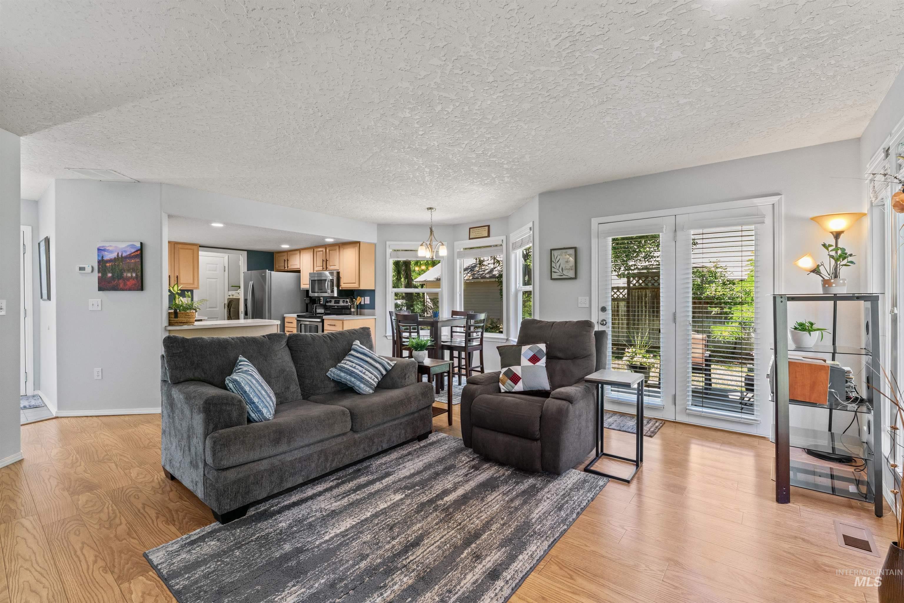 Living room featuring light wood-type flooring, a textured ceiling, and a chandelier