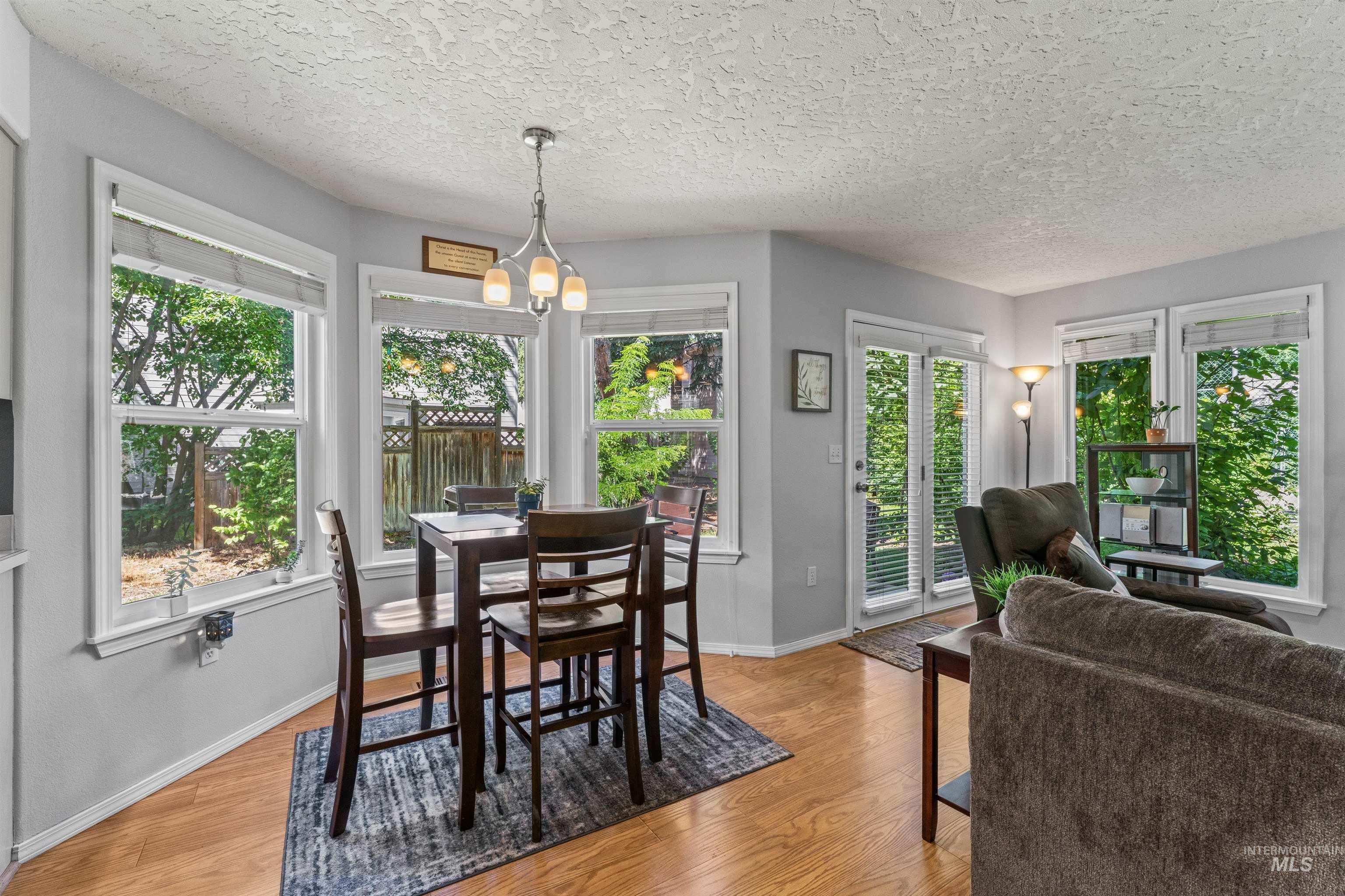 Dining space with light wood-style floors, a chandelier, and a textured ceiling