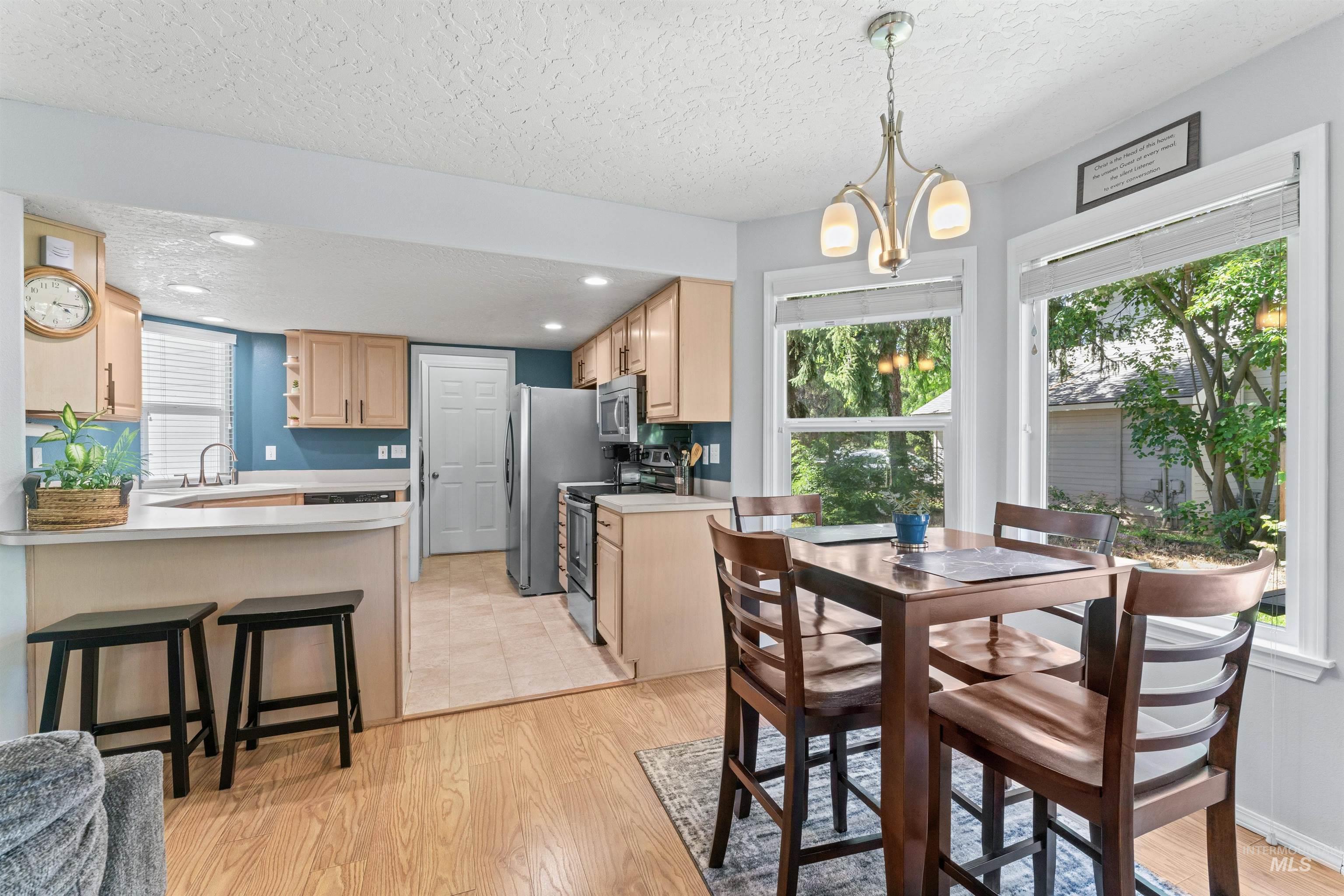Dining room featuring plenty of natural light, a textured ceiling, light wood finished floors, and a chandelier