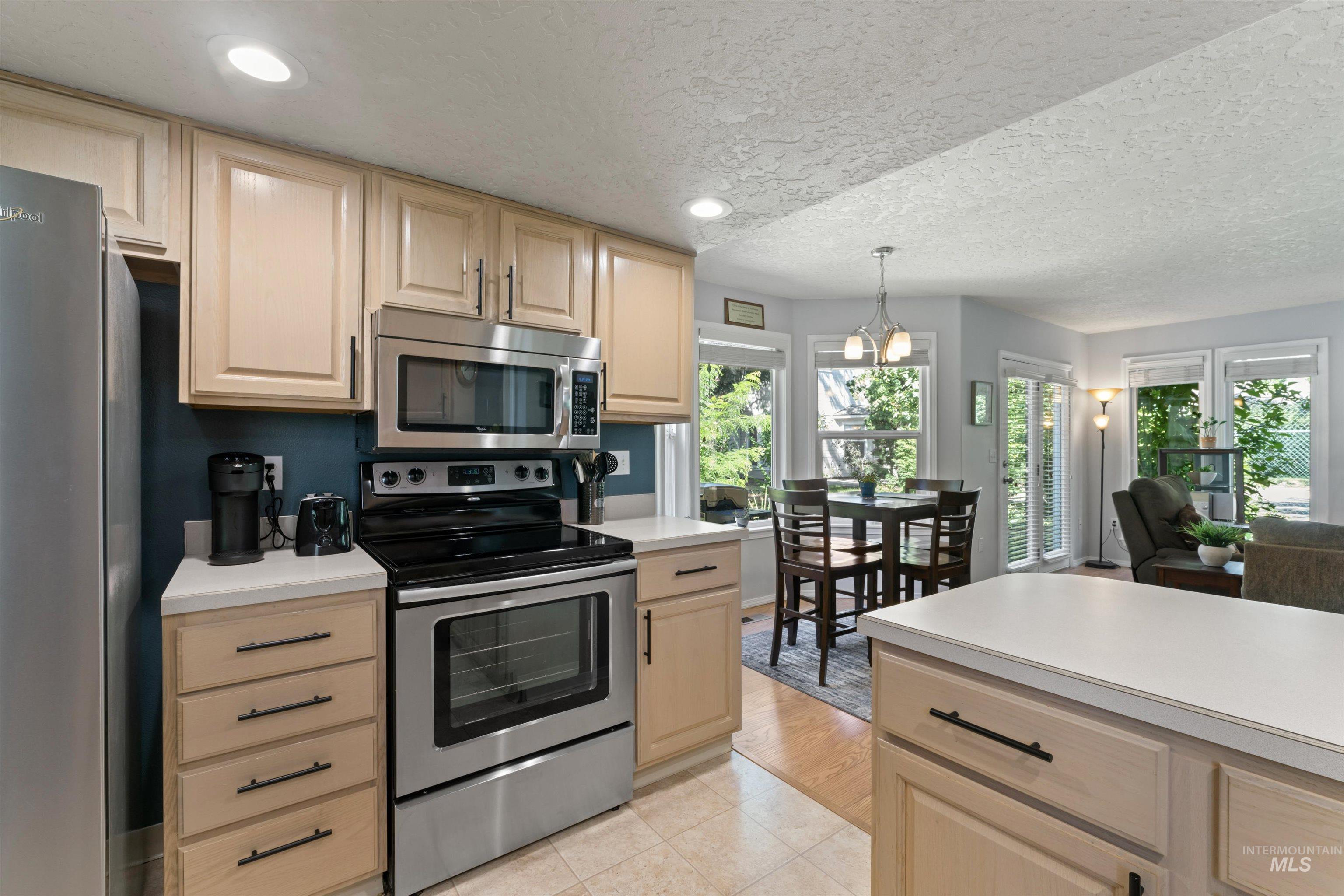Kitchen with appliances with stainless steel finishes, light brown cabinetry, light countertops, a textured ceiling, and recessed lighting
