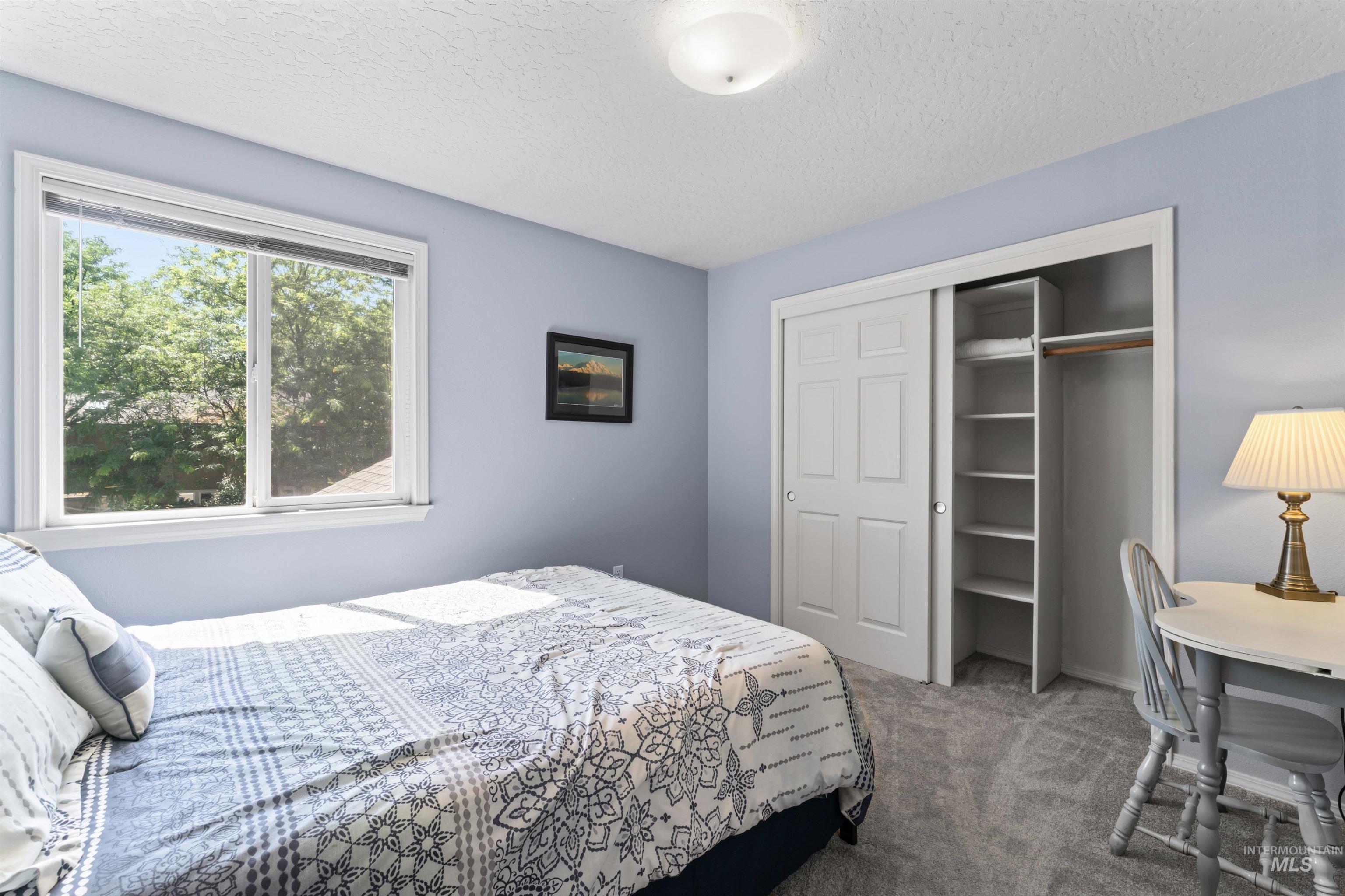 Carpeted bedroom featuring a textured ceiling and a closet