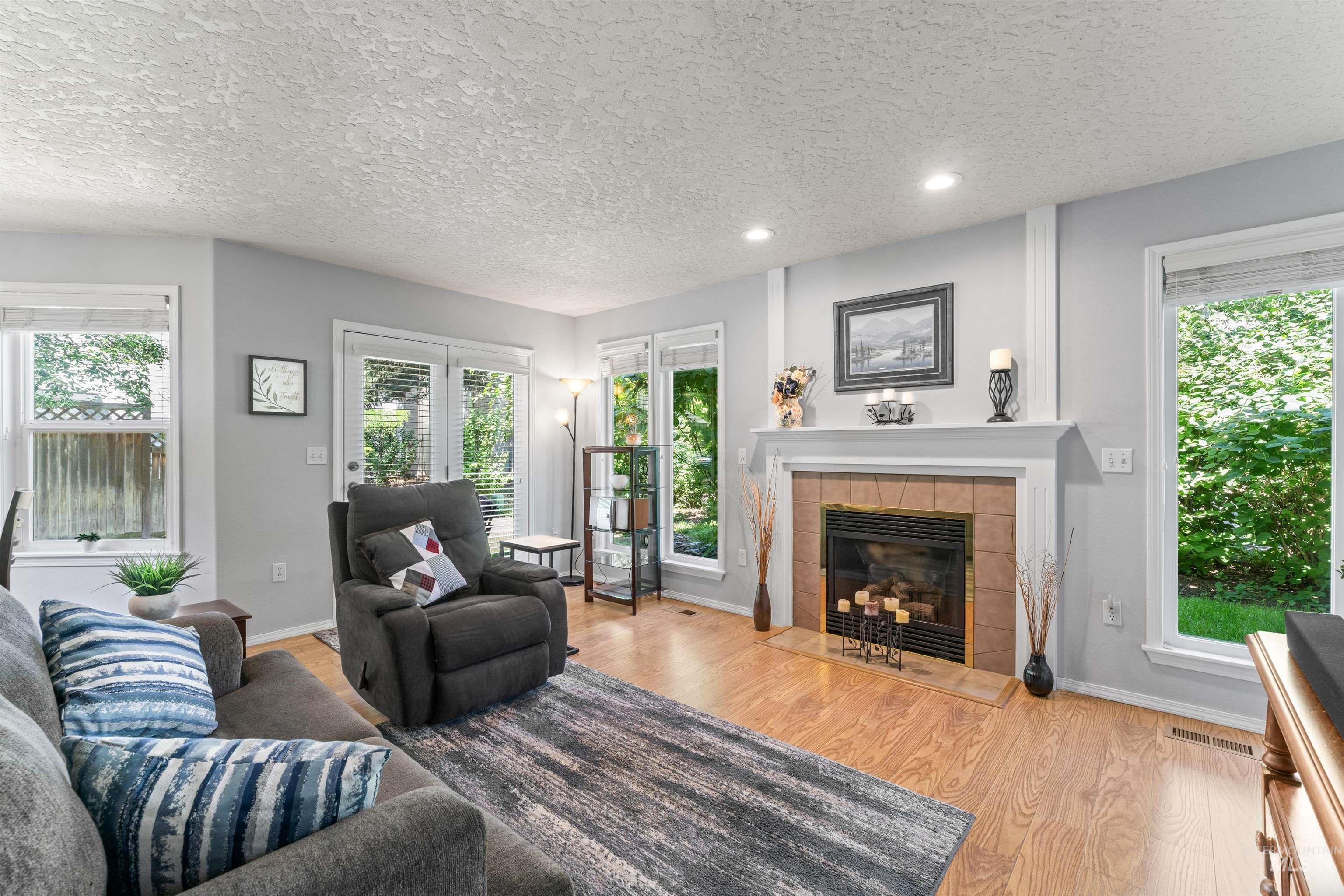 Living room featuring wood finished floors, a fireplace, healthy amount of natural light, a textured ceiling, and recessed lighting