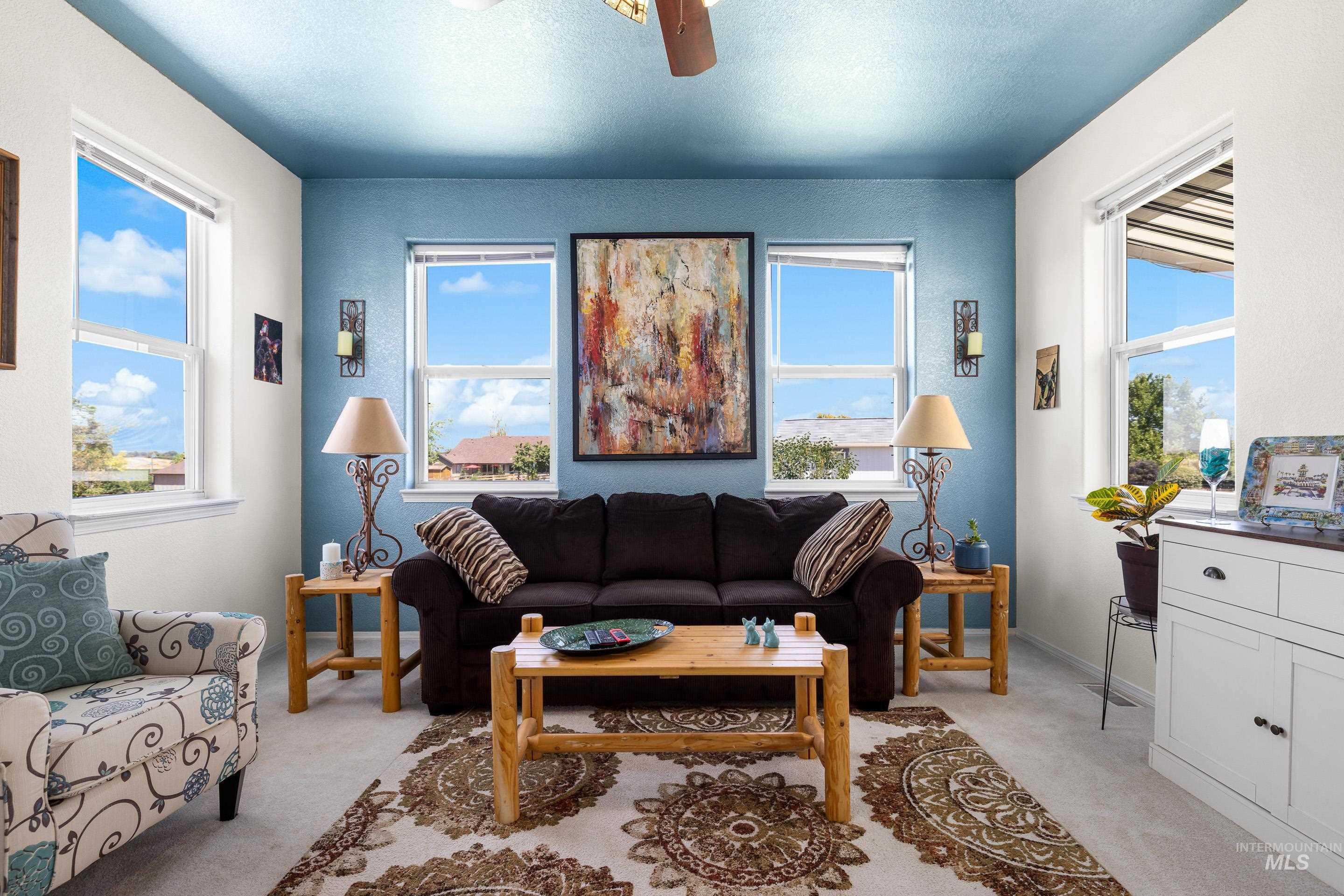 Living room featuring light colored carpet, ceiling fan, plenty of natural light, and a textured ceiling