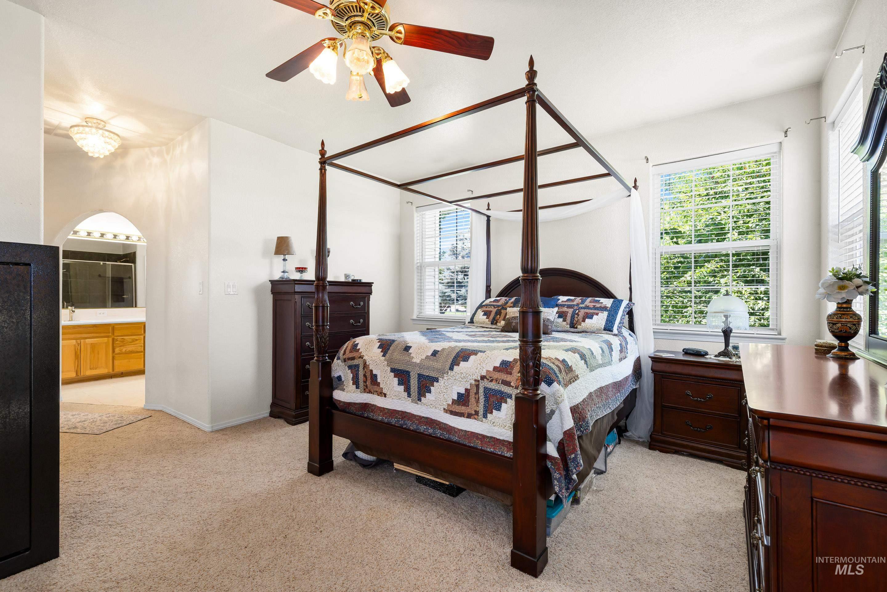 Bedroom with light carpet, ceiling fan, and ensuite bath