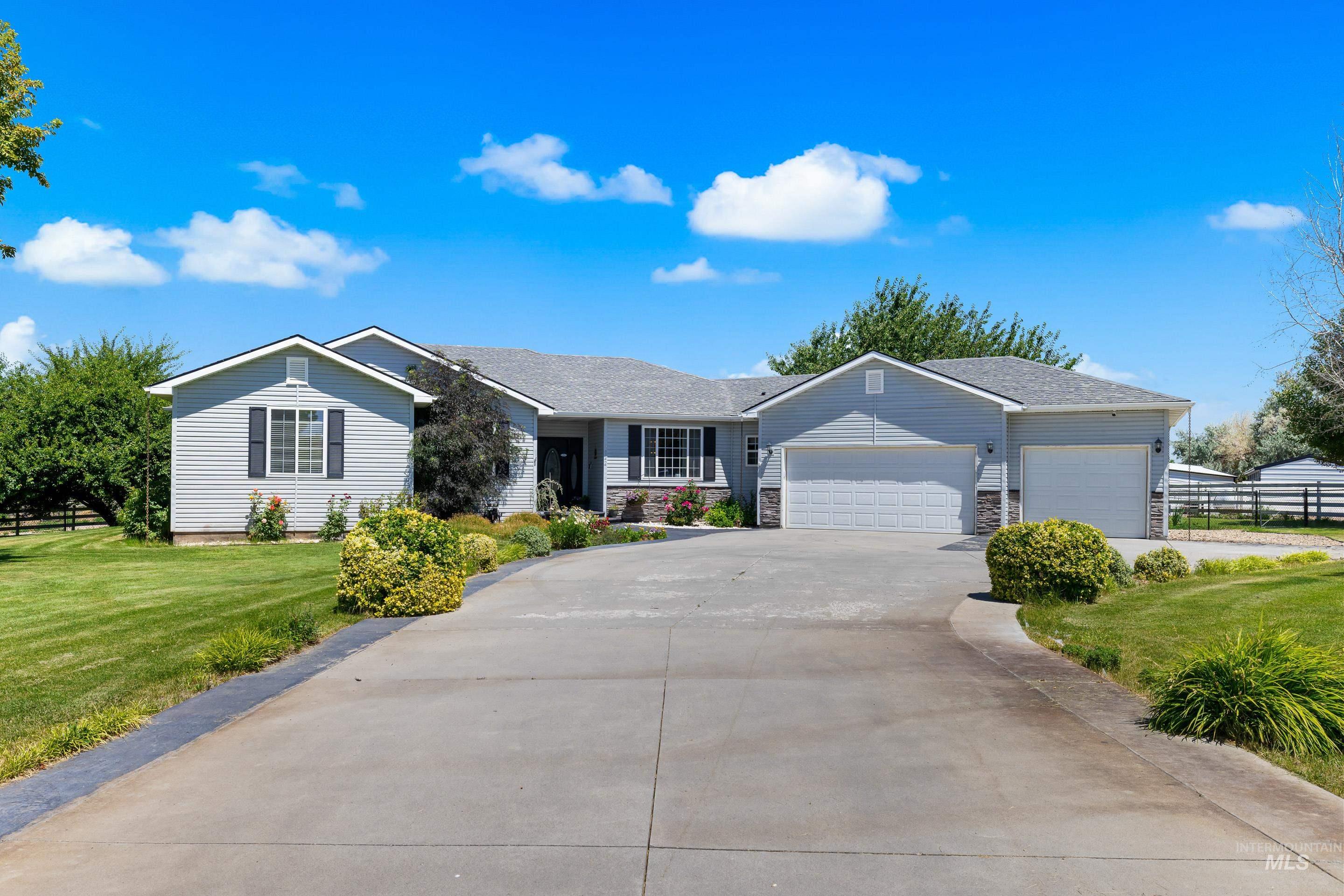 Ranch-style home with a garage, concrete driveway, stone siding, and a shingled roof