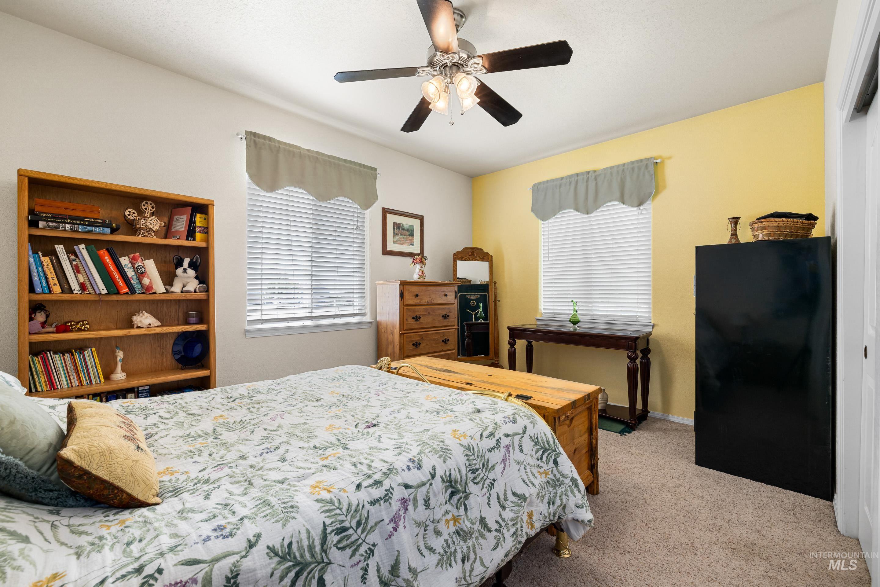 Bedroom with light colored carpet, multiple windows, and ceiling fan
