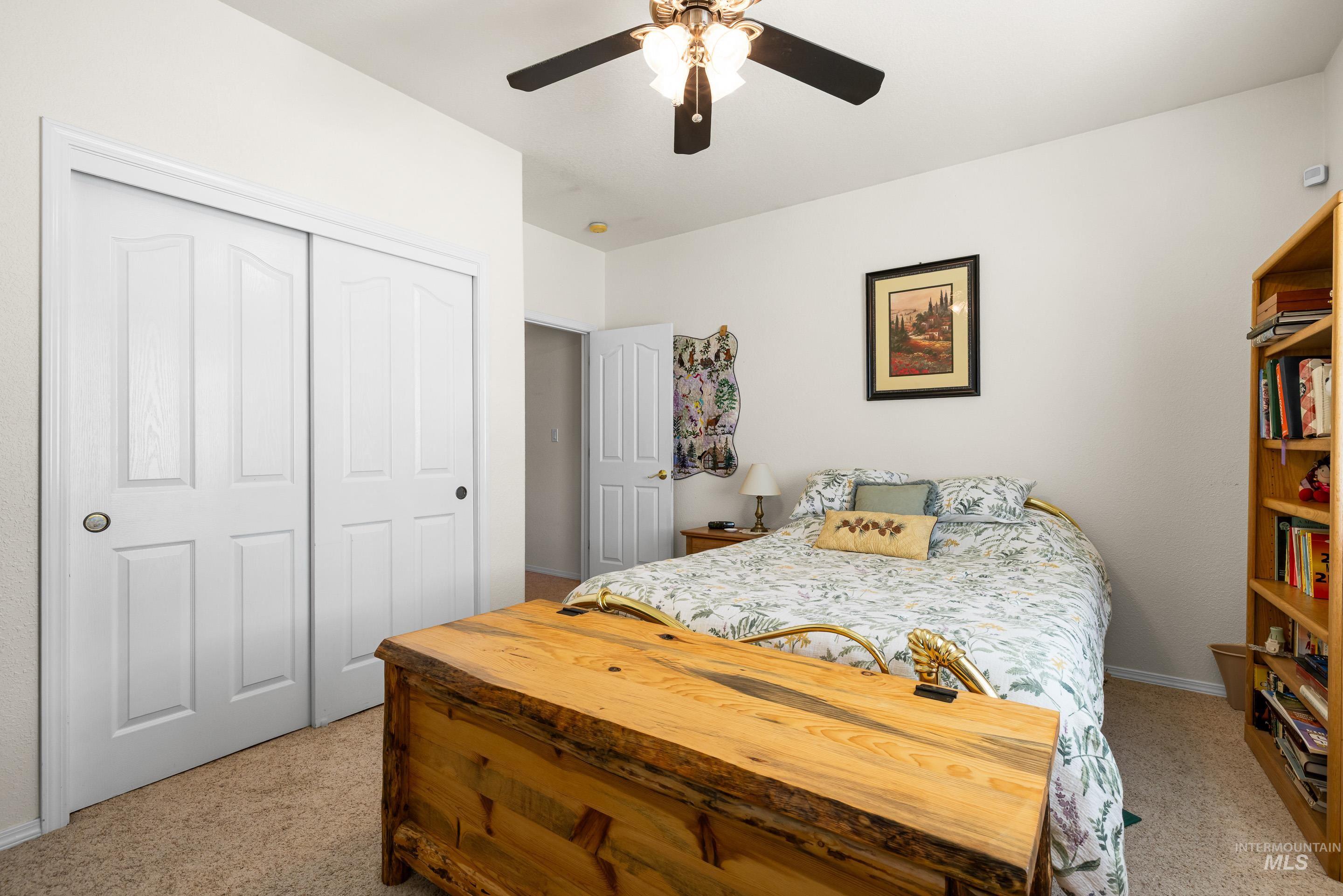 Bedroom featuring a ceiling fan, light carpet, and a closet